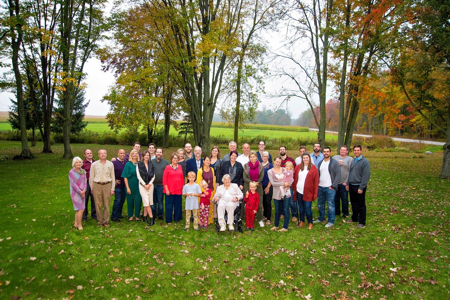 Large extended family group portrait taken outdoors on a green lawn in autumn.