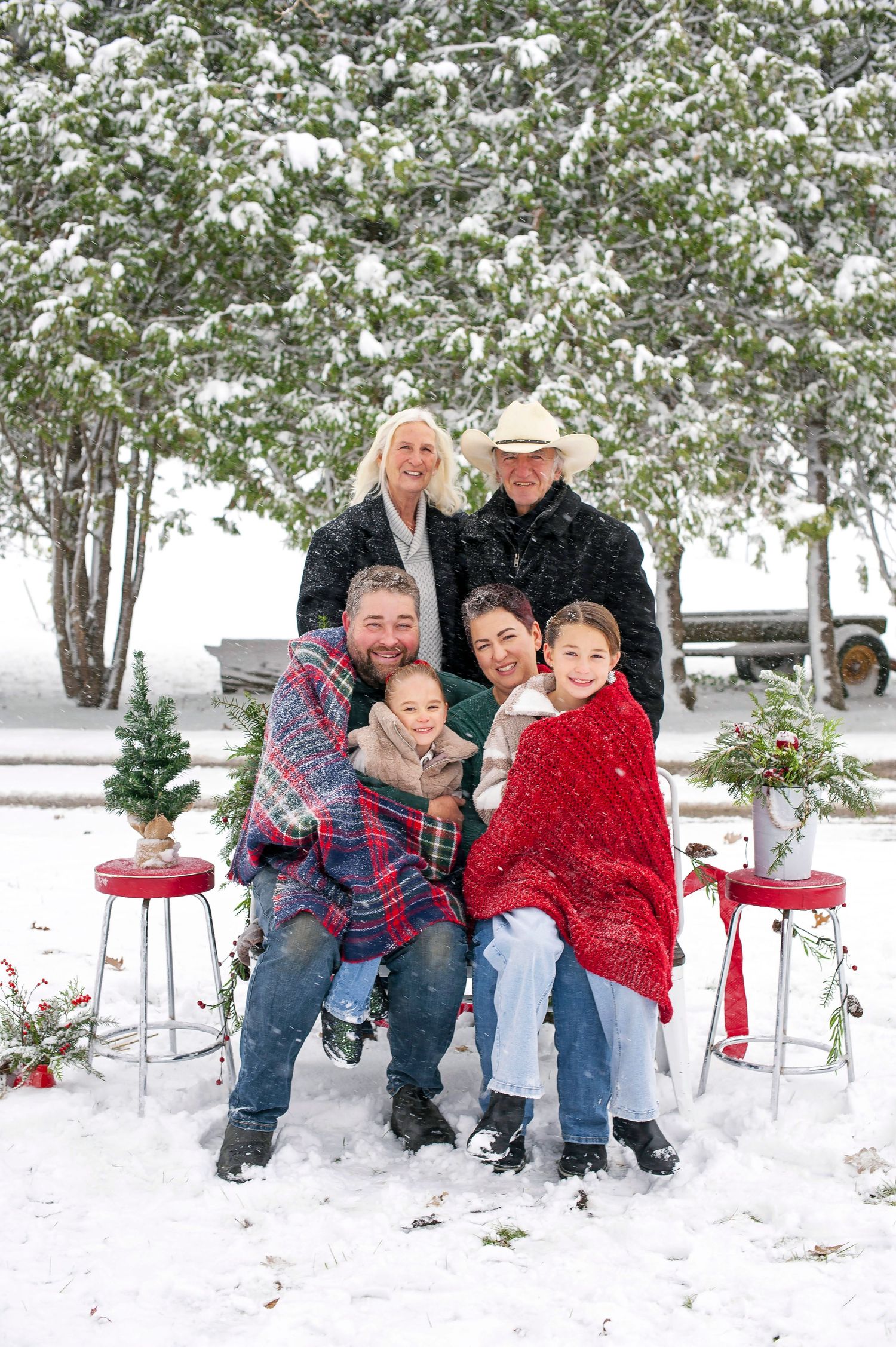 Multi-generational family posing outdoors in snow for Christmas portrait.