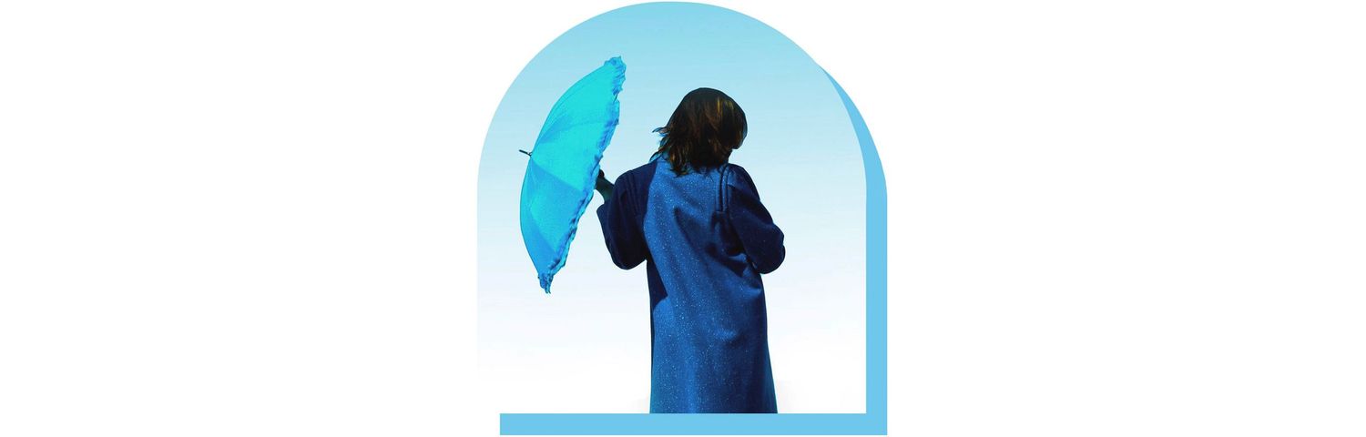 Person in blue raincoat holding turquoise umbrella standing in arched window during rain.