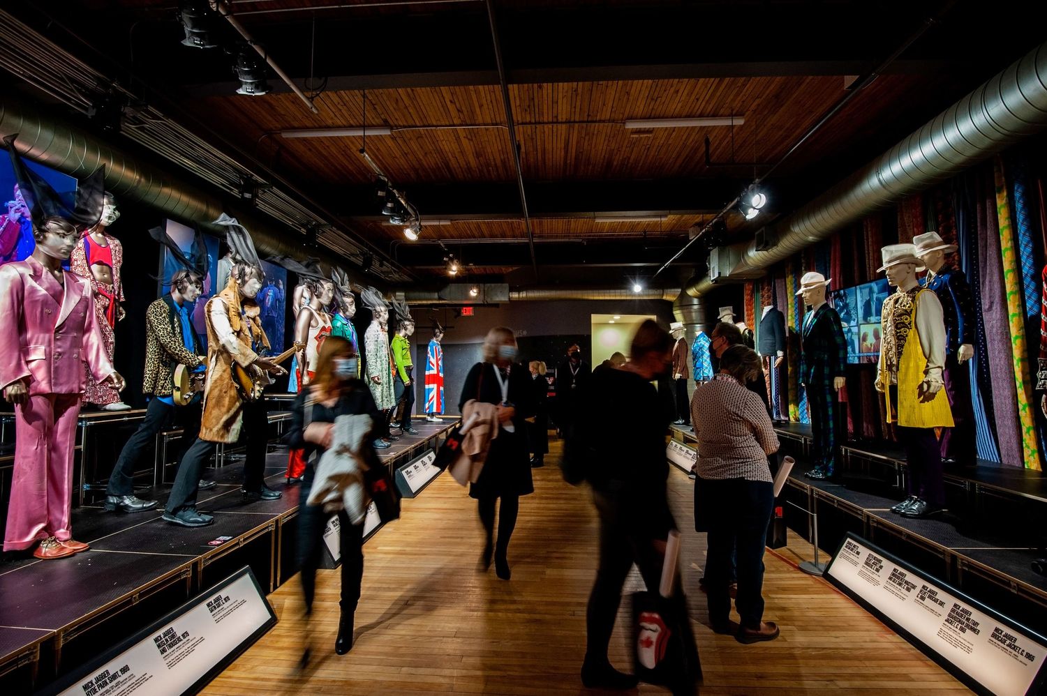 Wide view of a rock music museum exhibit featuring iconic stage costumes on mannequins.