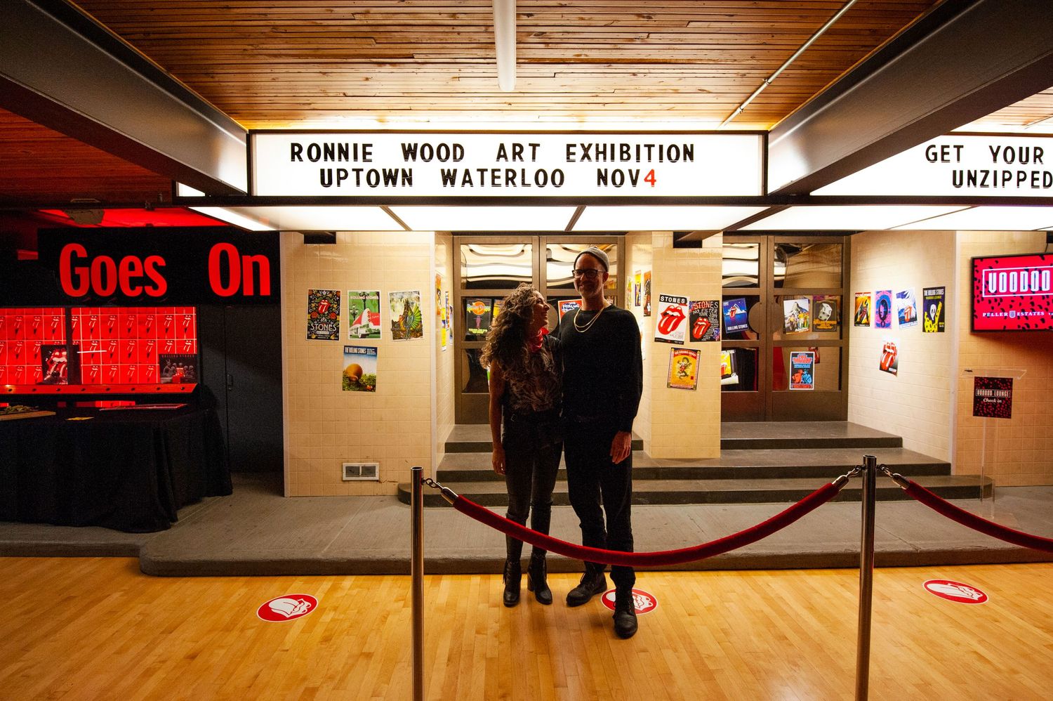 Couple posing under Ronnie Wood Art Exhibition marquee sign at Uptown Waterloo venue.