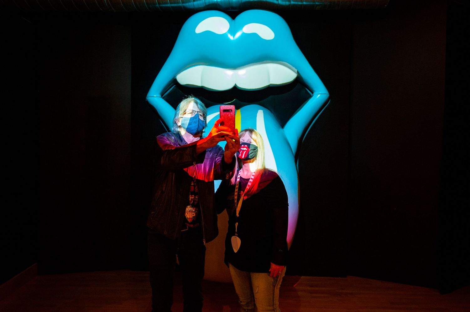 Visitors take a selfie with a large illuminated Rolling Stones lips and tongue sculpture.