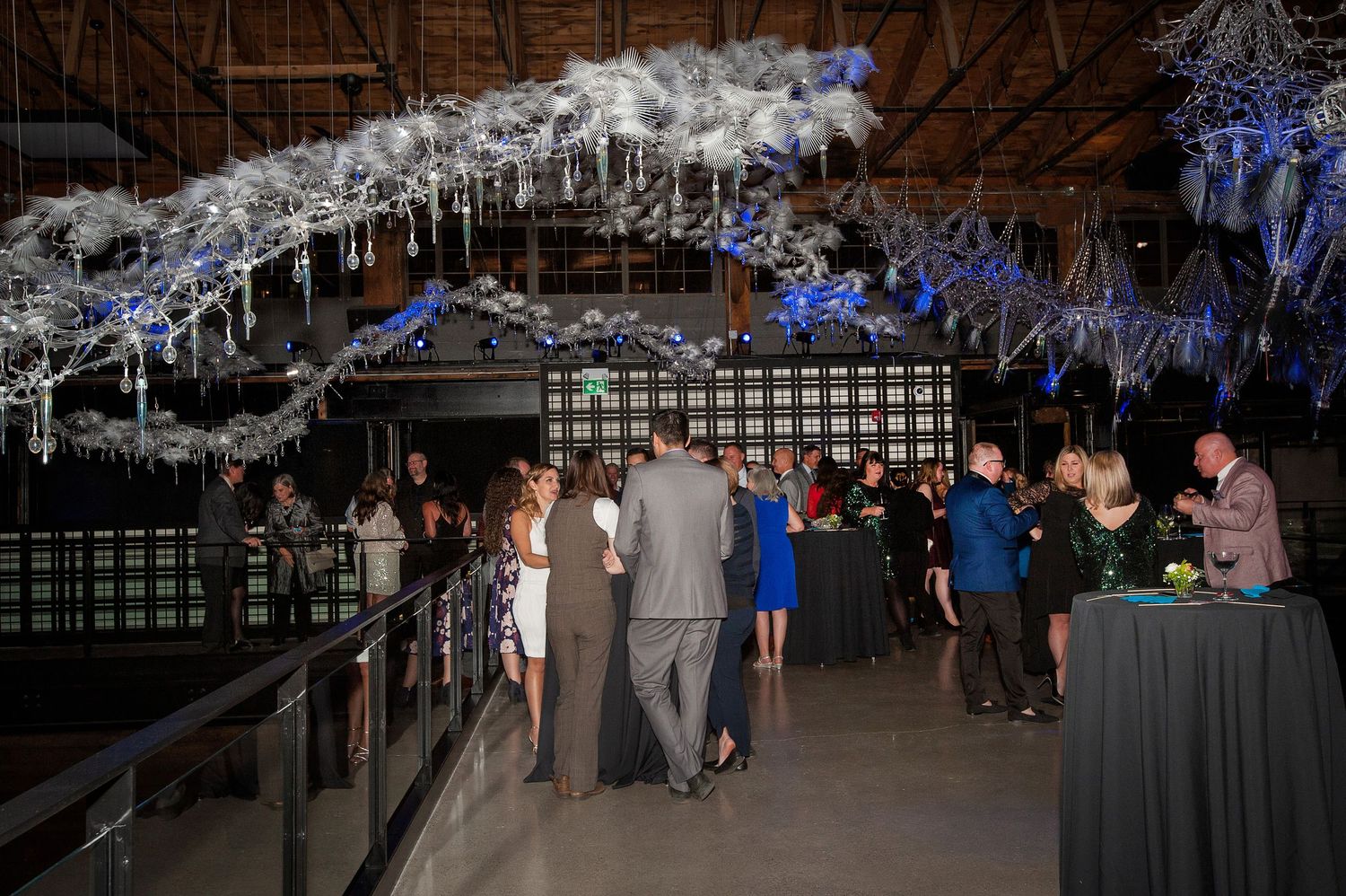 Guests mingling under white icicle ceiling decorations at an upscale indoor evening reception.