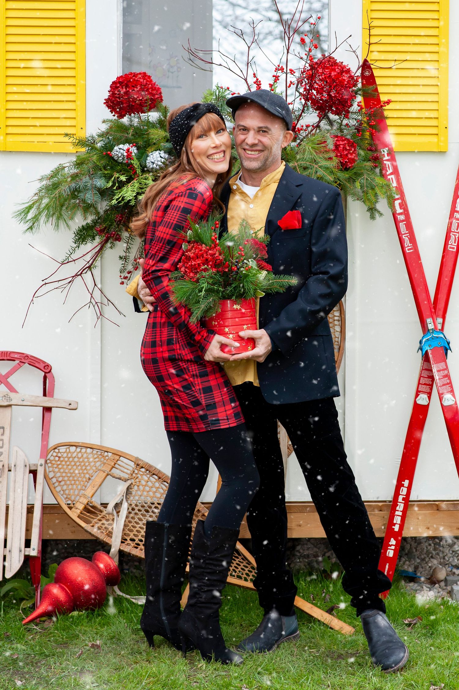 Couple embracing outdoors in festive holiday attire with Christmas decorations in snow.