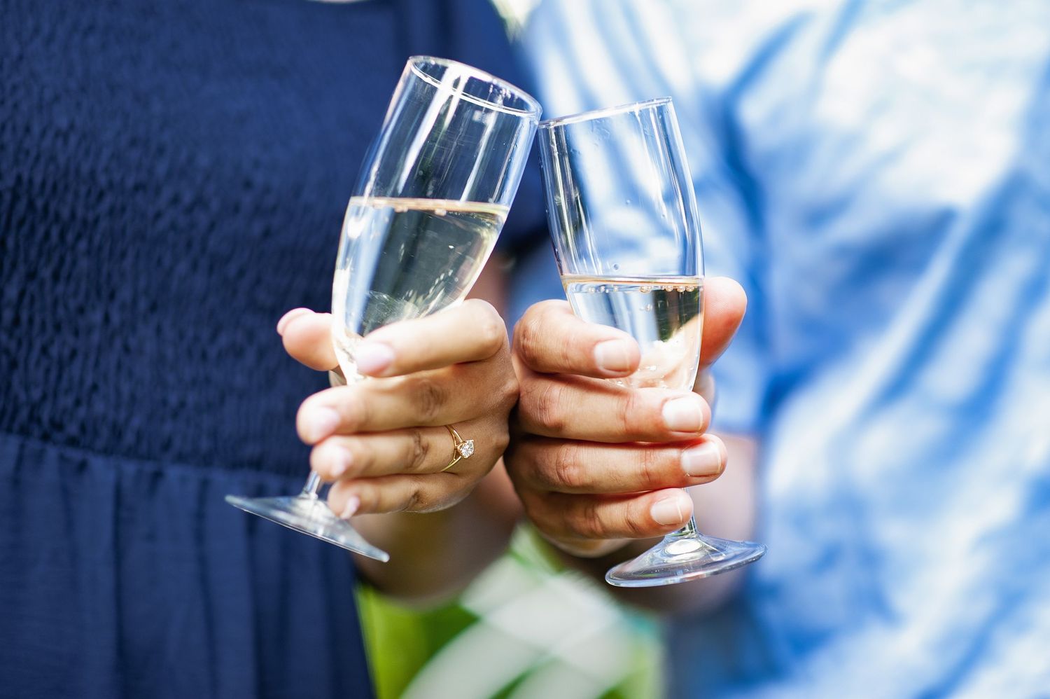 Couple toasting with champagne glasses in an outdoor celebration after engagement.