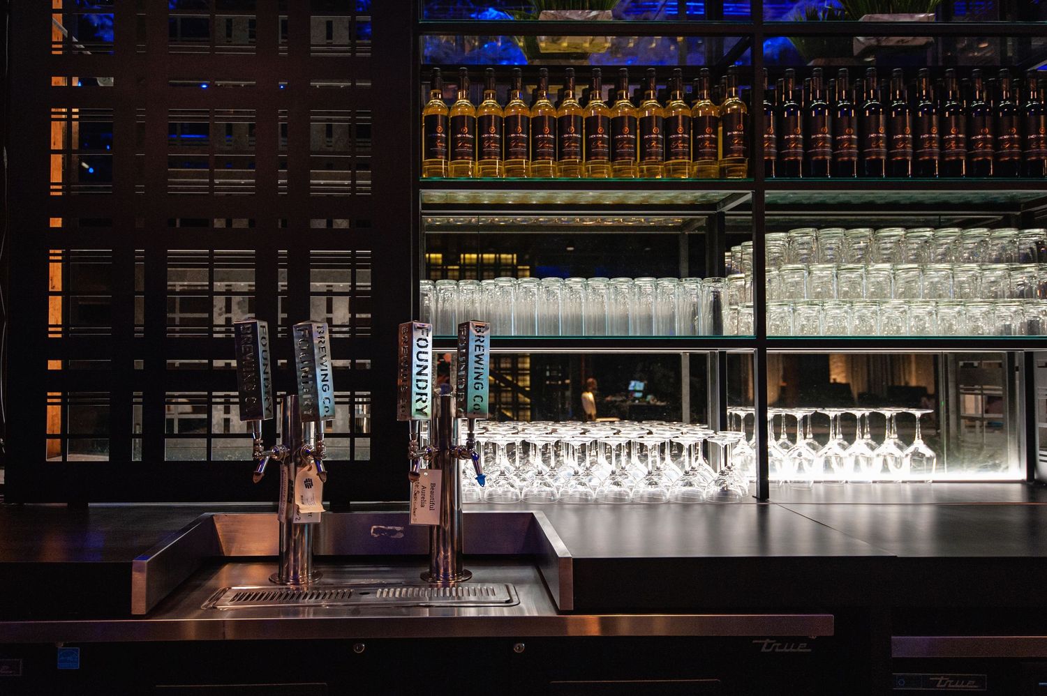 Elegant bar setup with beer taps and rows of wine glasses at an upscale venue.