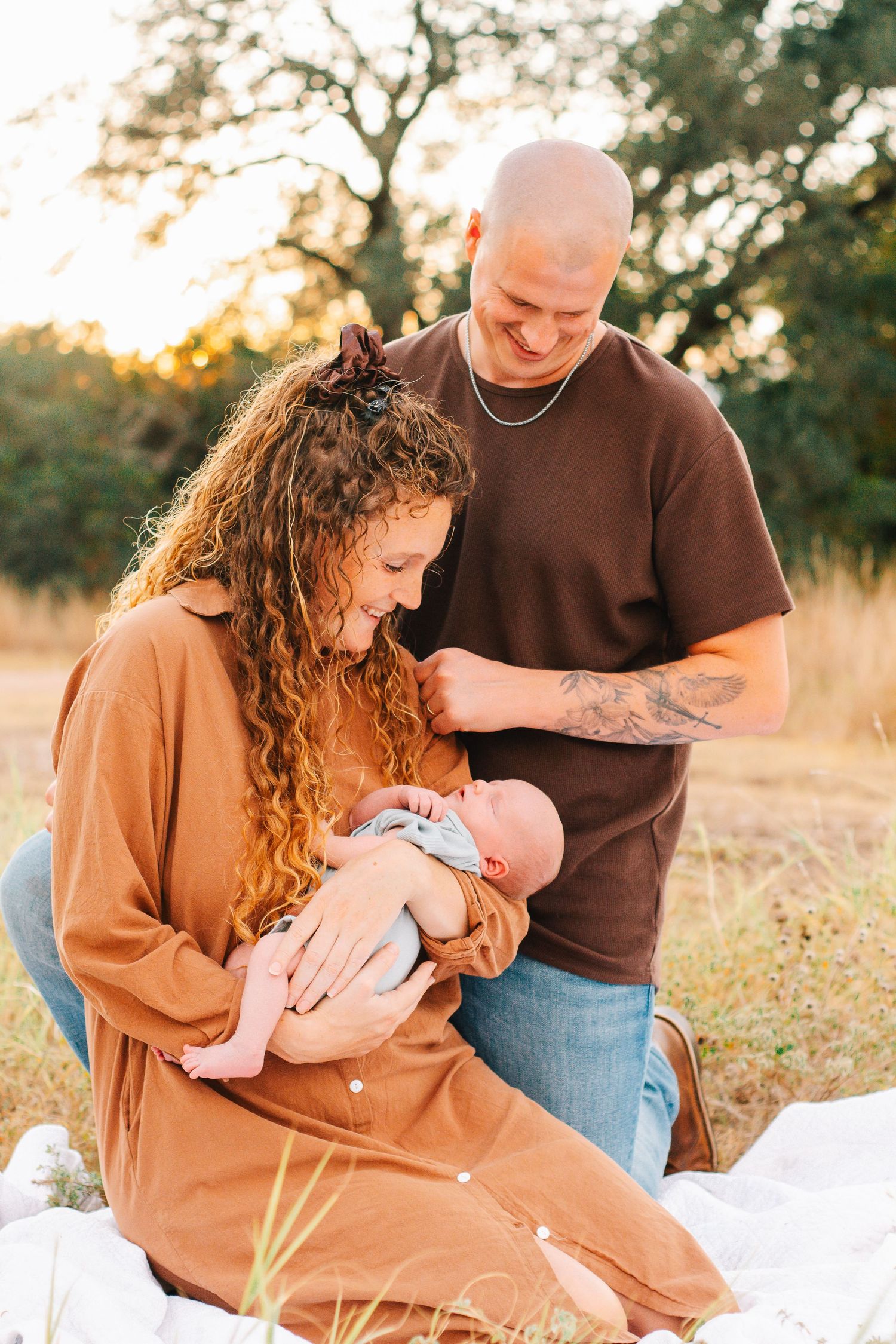 Family enjoying tender moments together on a picnic blanket during golden hour sunset.