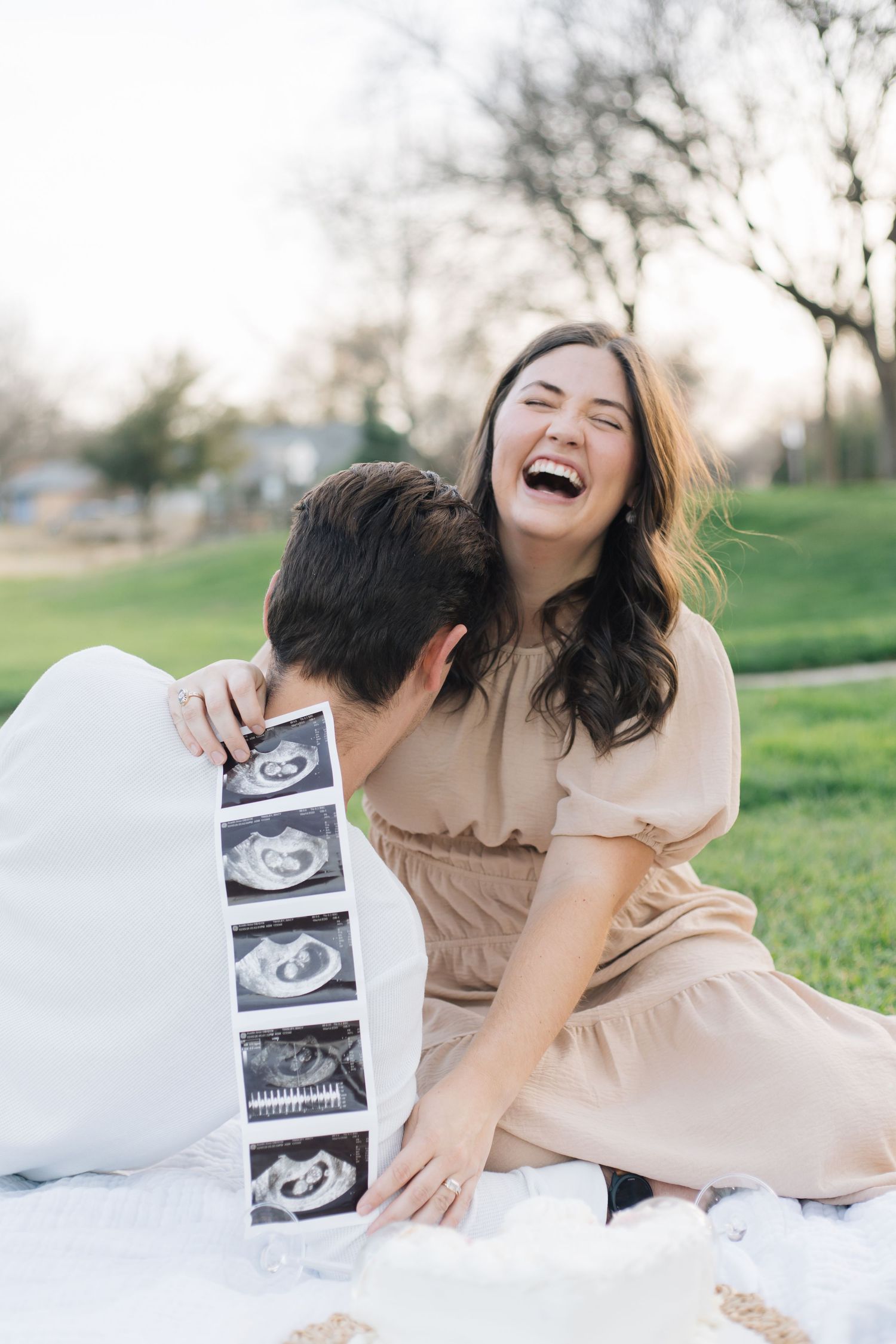 Candid moment of joy captured during pregnancy announcement photoshoot on picnic blanket.