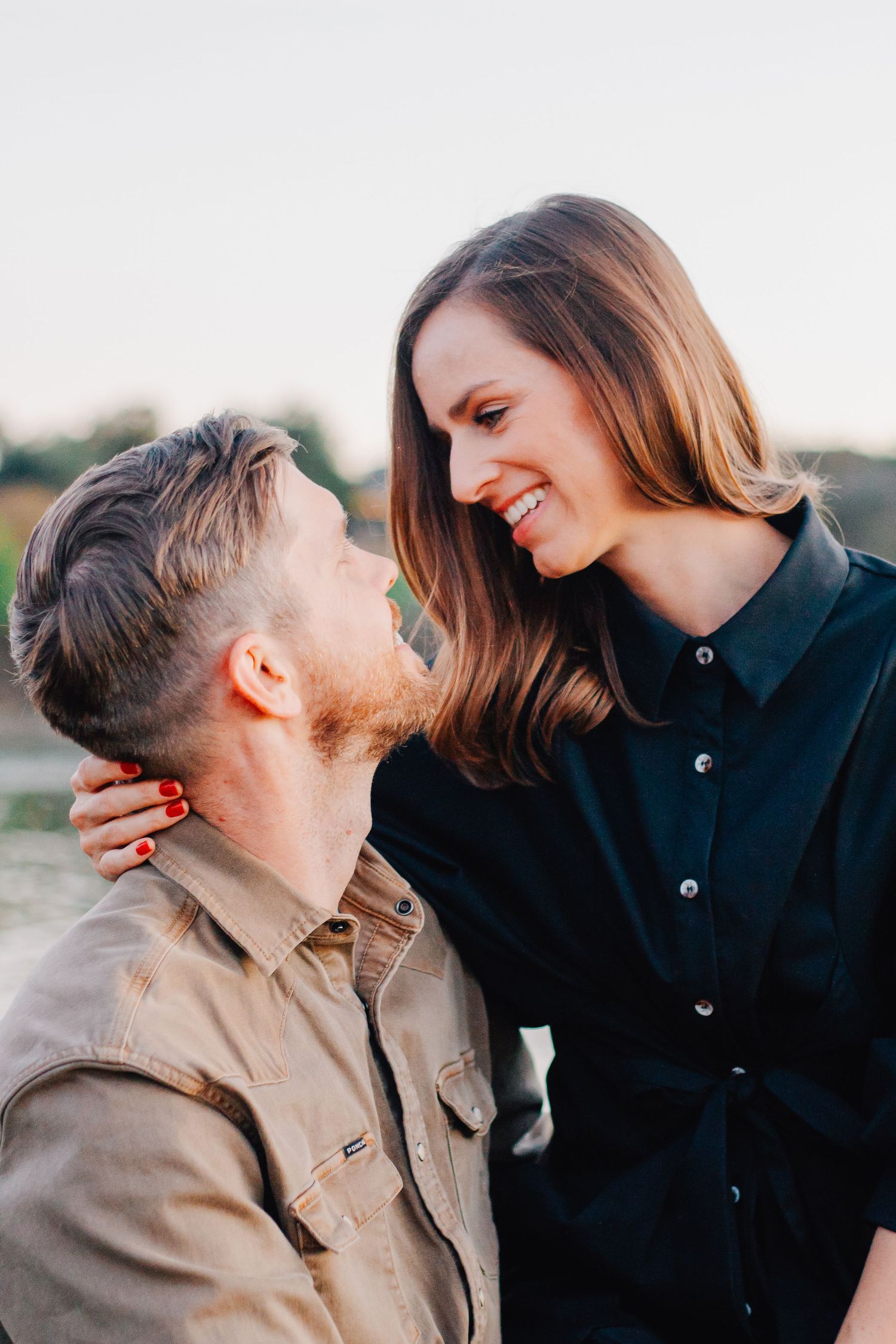 A couple shares a joyful laugh together during an outdoor photoshoot.