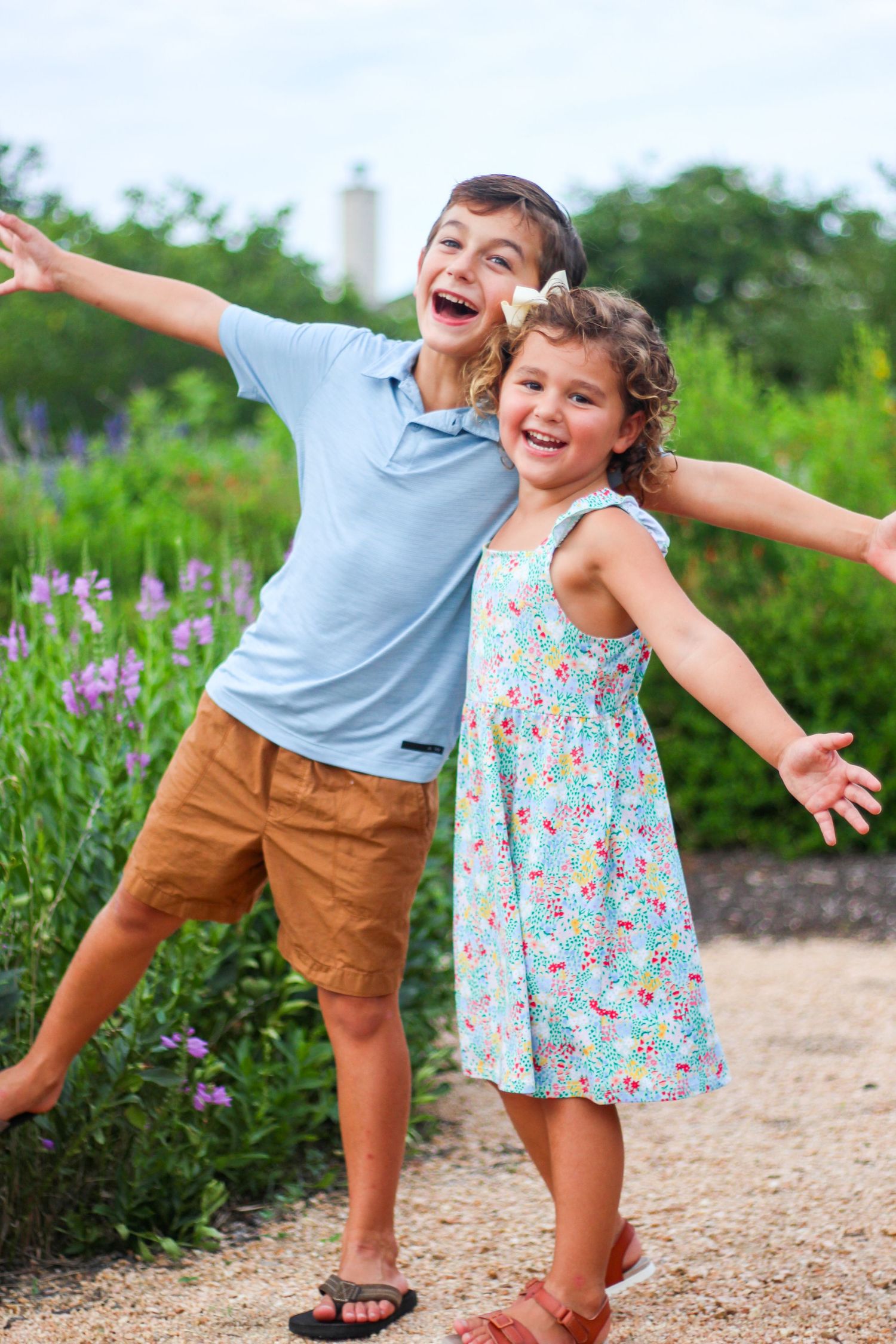 Playful outdoor photoshoot with purple wildflowers along a dirt path.