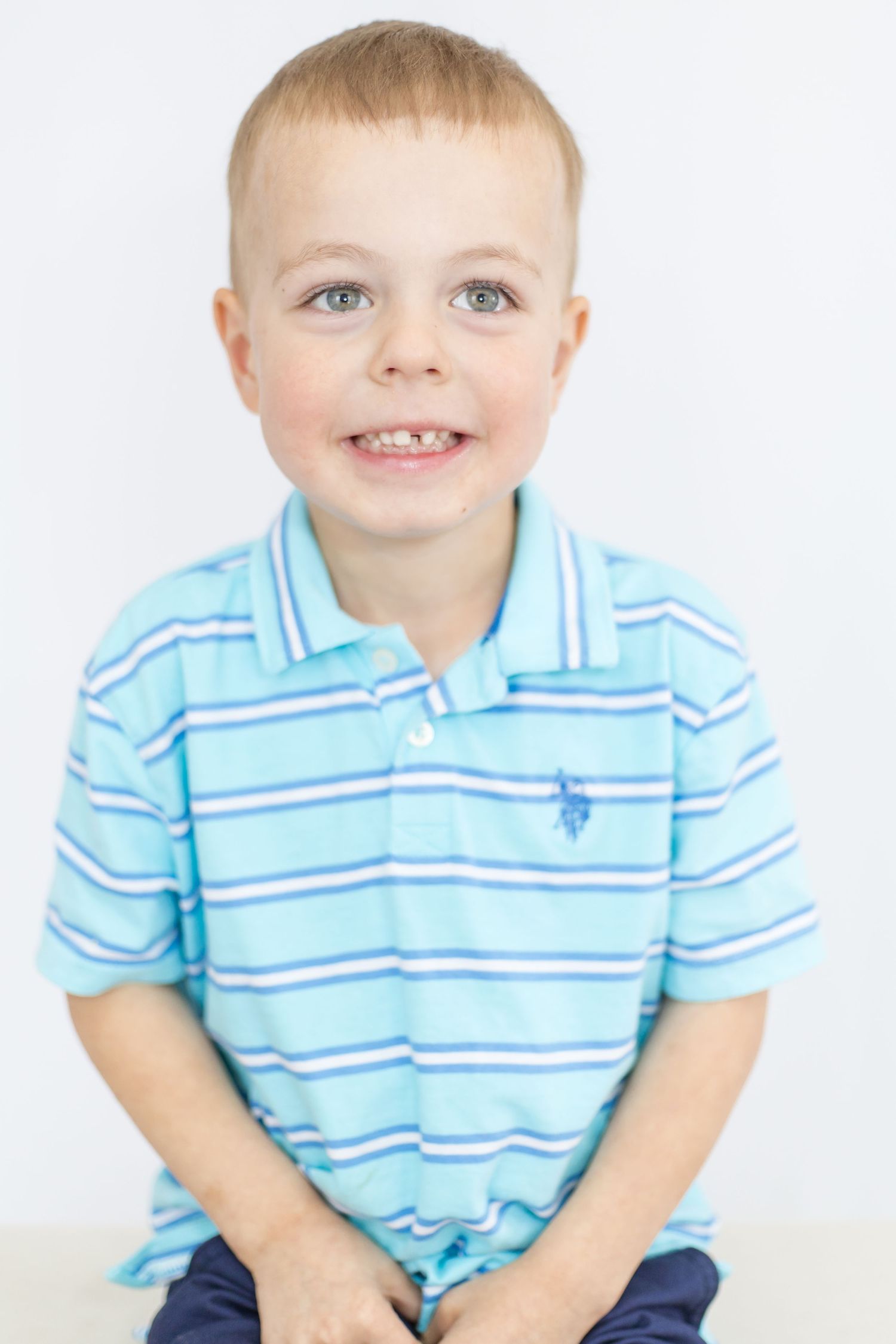 Portrait series in light blue striped polo shirt against white backdrop.