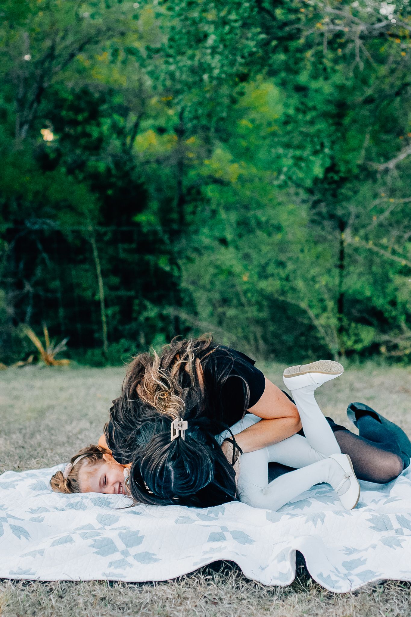 Series of artistic photos showing a couple lying on a white blanket in a natural outdoor setting.