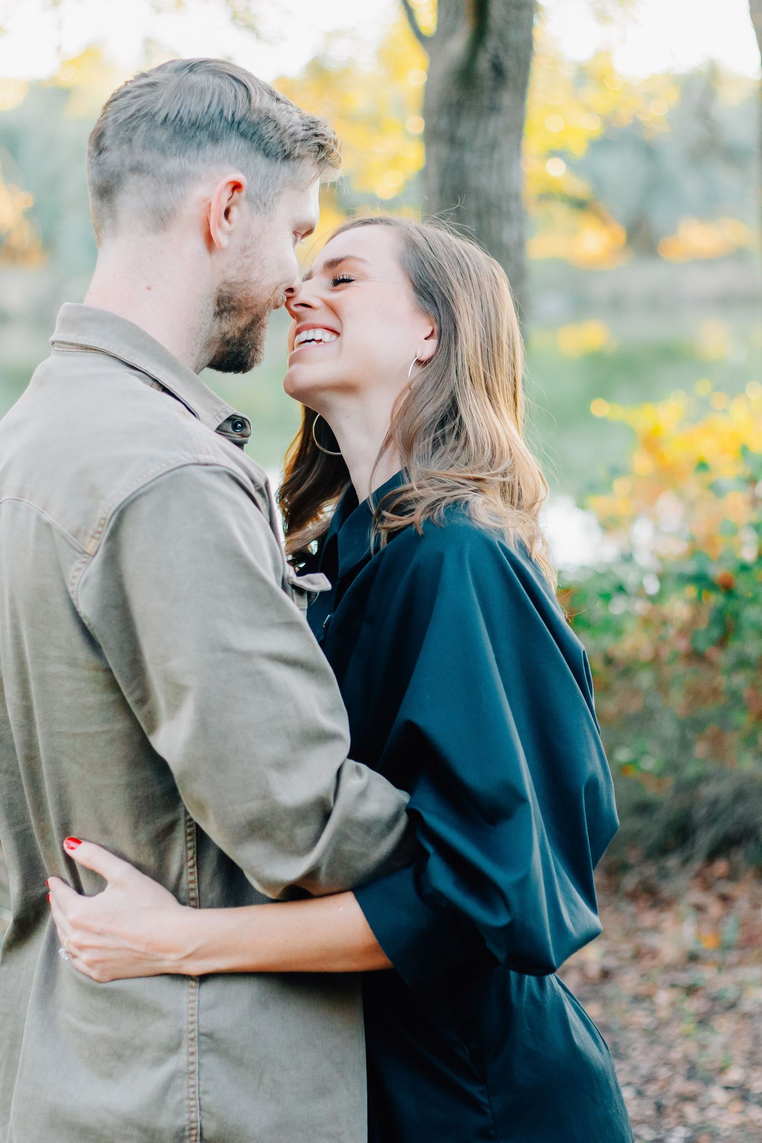 Romantic couple embracing and laughing together in autumn outdoor setting.