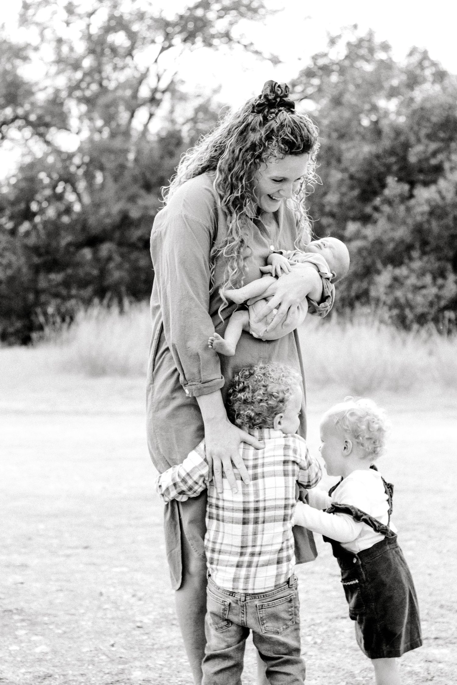 Black and white photo of family embracing in outdoor field setting.