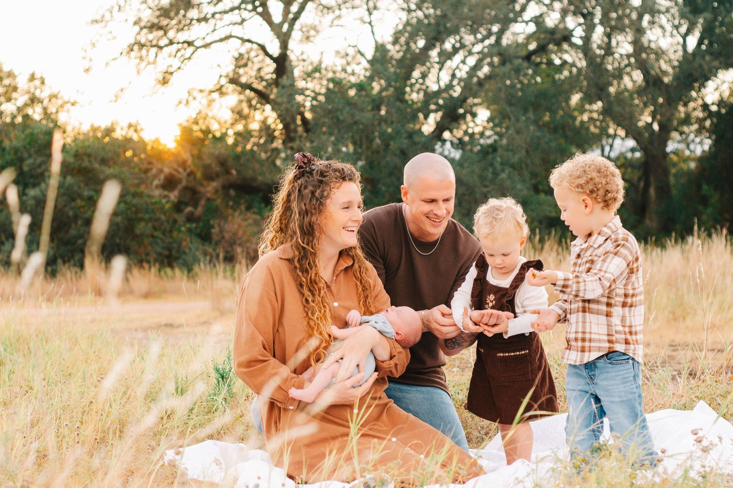 Family portrait session in golden field during sunset with natural lighting.
