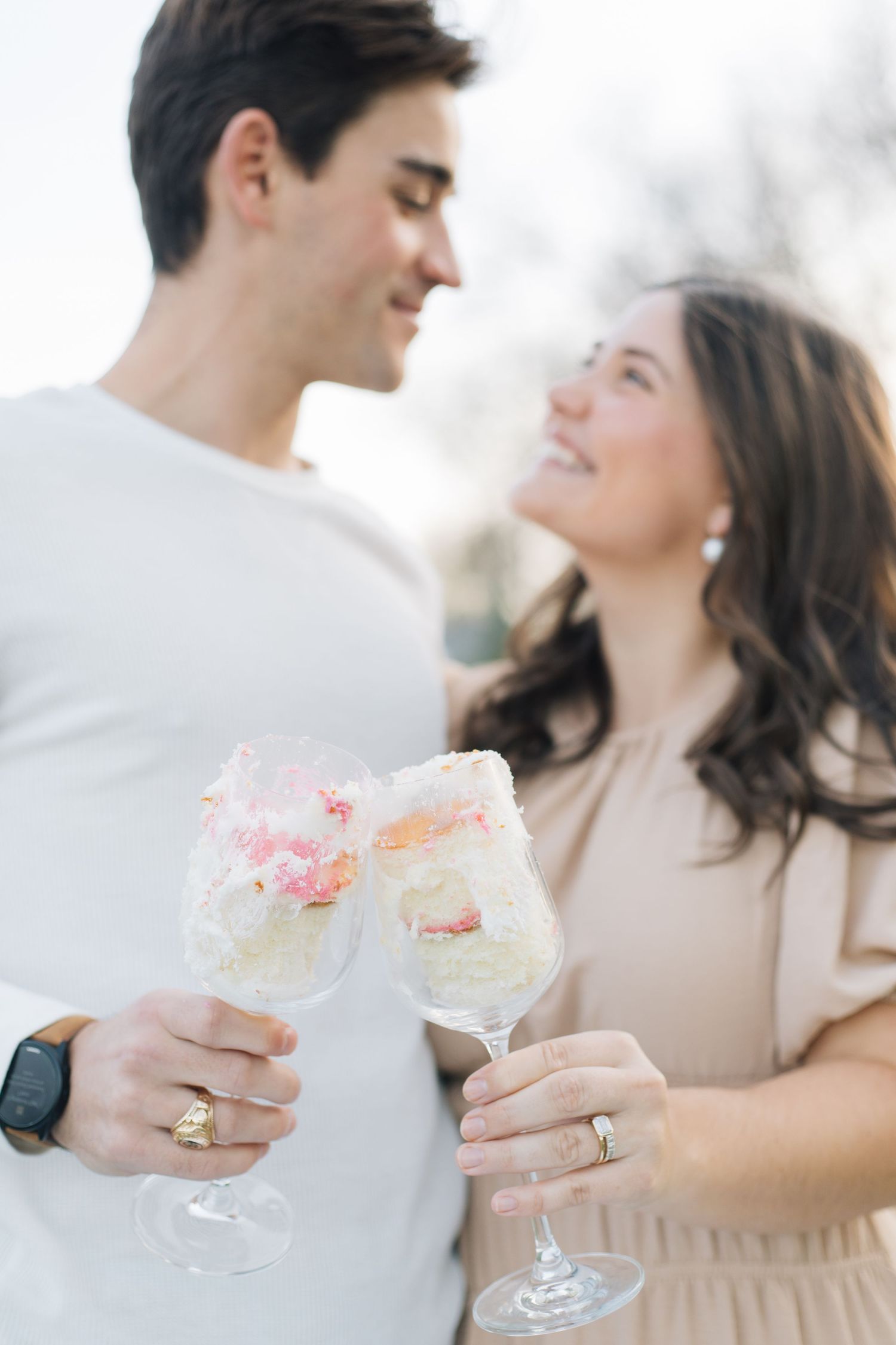 Couple toasts with pink drinks while sharing romantic moment outdoors.