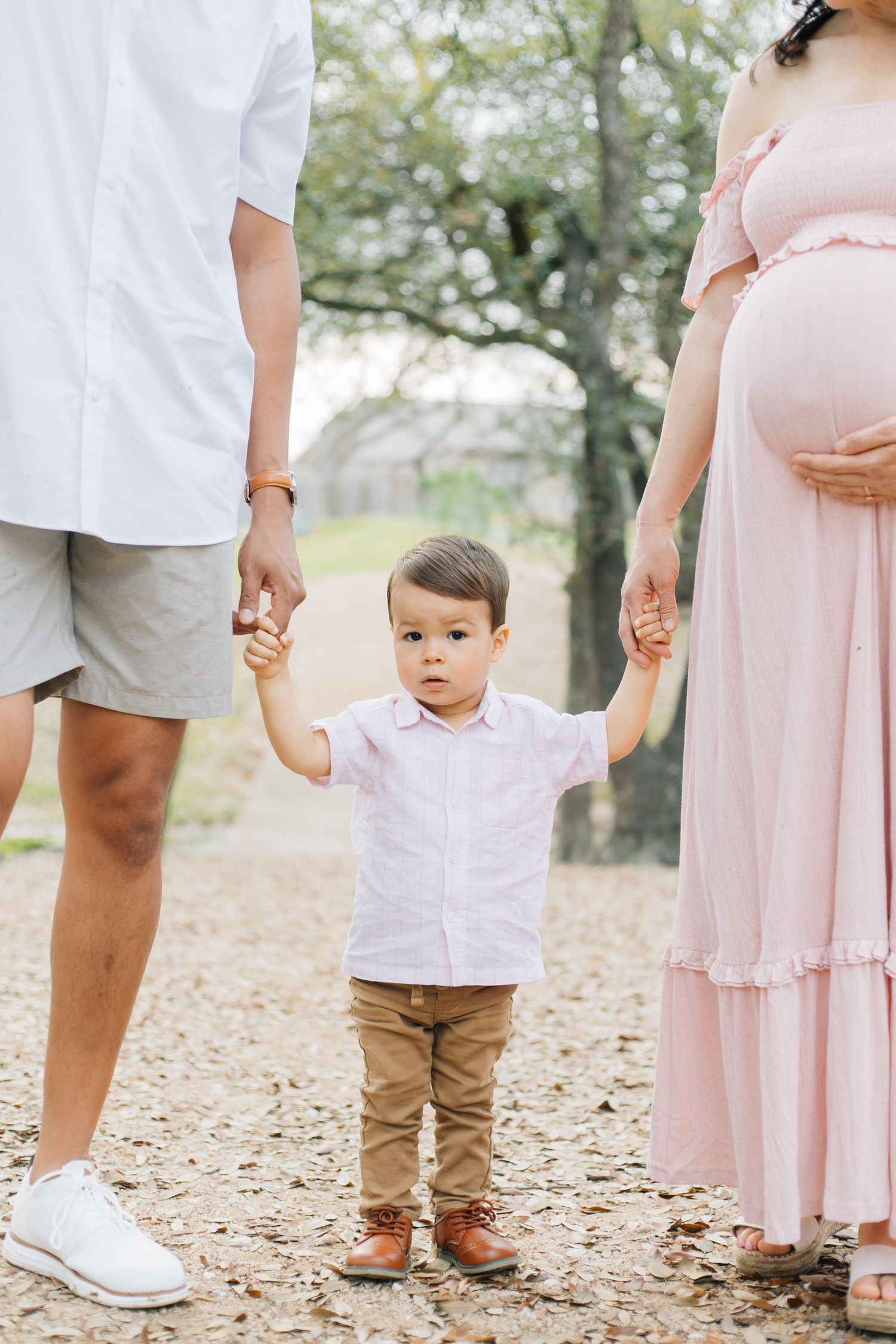 Family members stand together on leaf-covered ground wearing coordinated casual outfits.