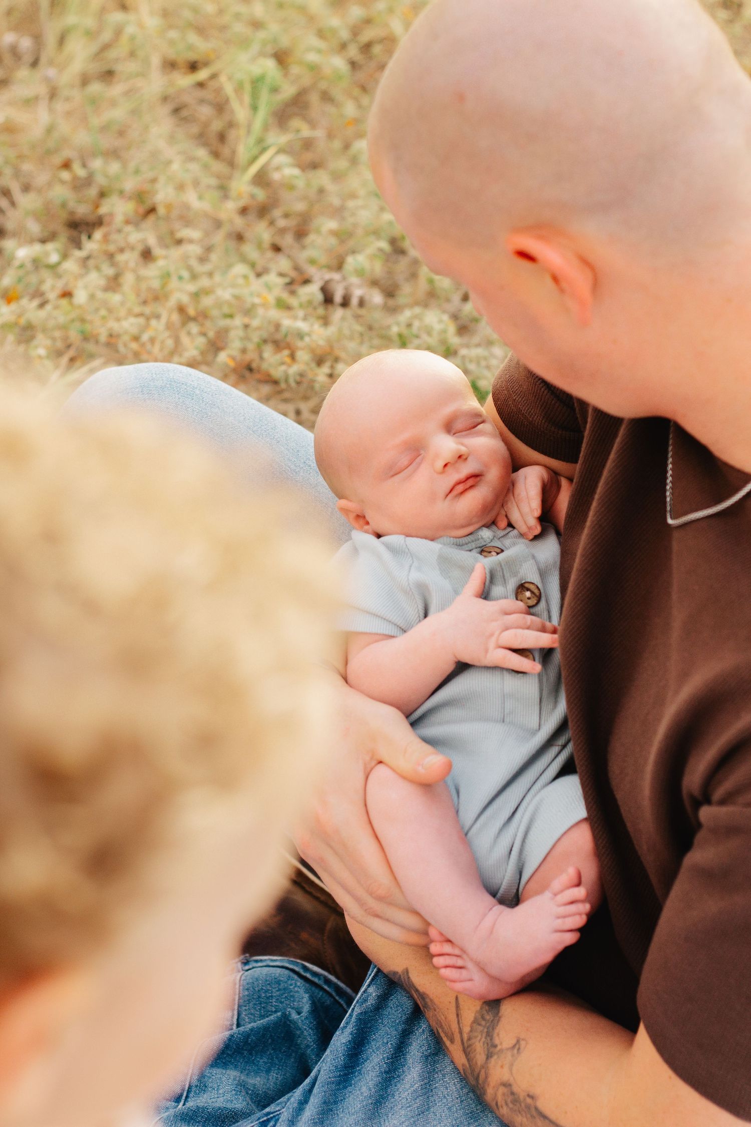 A tender moment between parent and infant in soft lighting against a natural background.