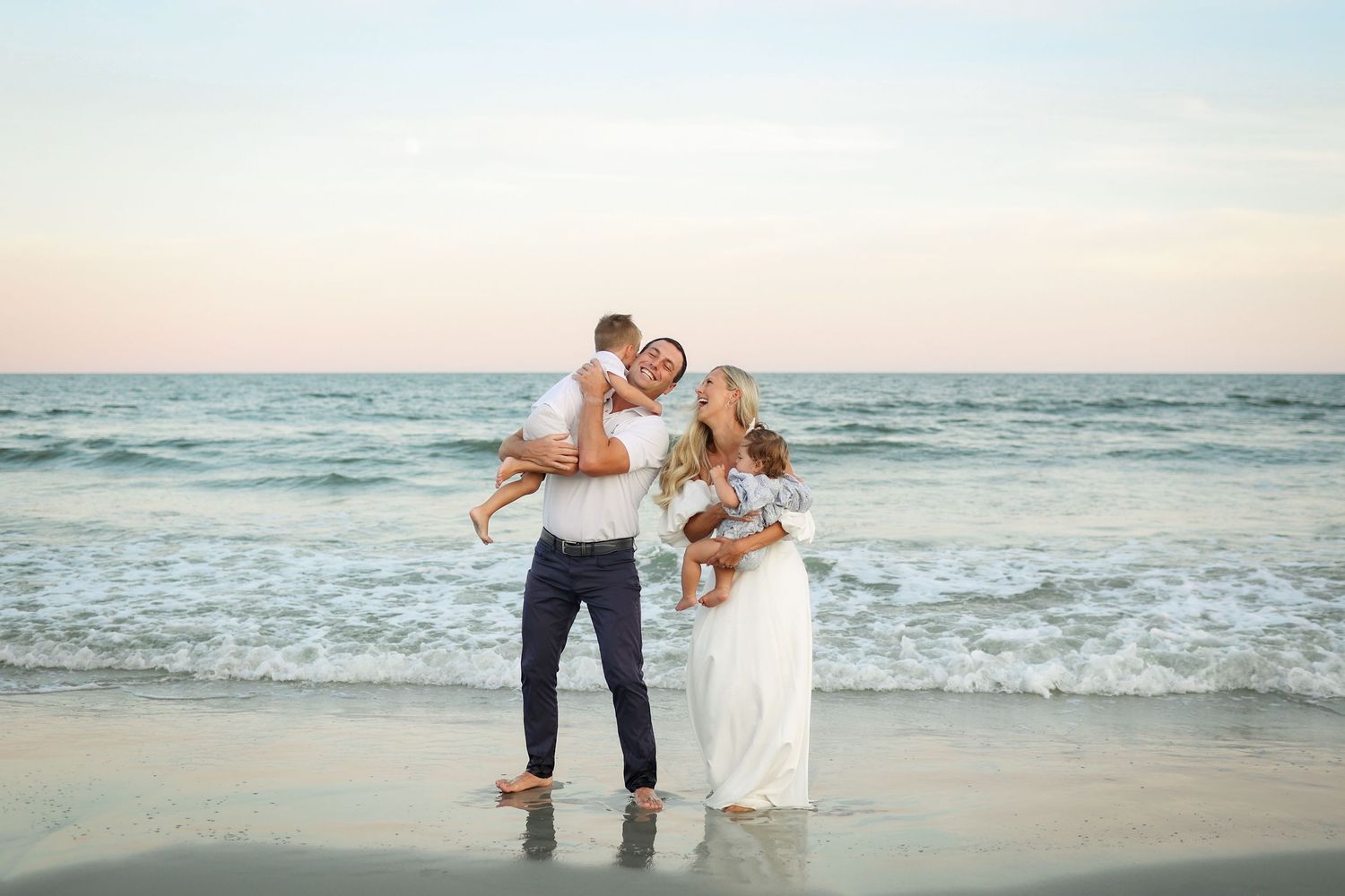Hilton Head family photos of a young family smiling together in front of the ocean at Palmetto Dunes beach