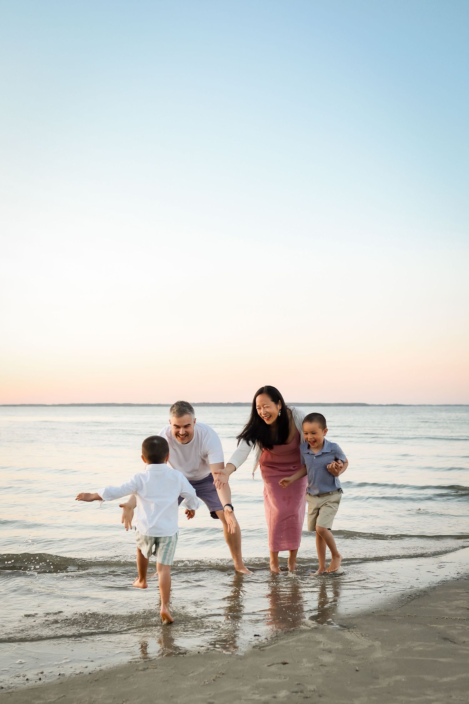 Family photo session on Hilton Head at Fish Haul Beach as parents smile while their youngest child runs to them