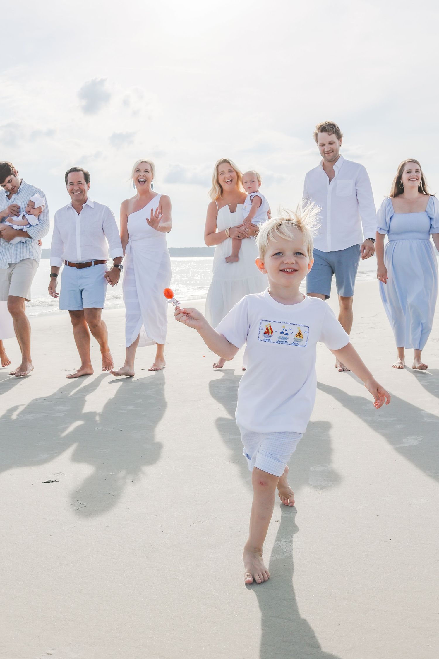 Extended family reunion photos on Hilton Head beach with grandson running toward camera as family laughs together
