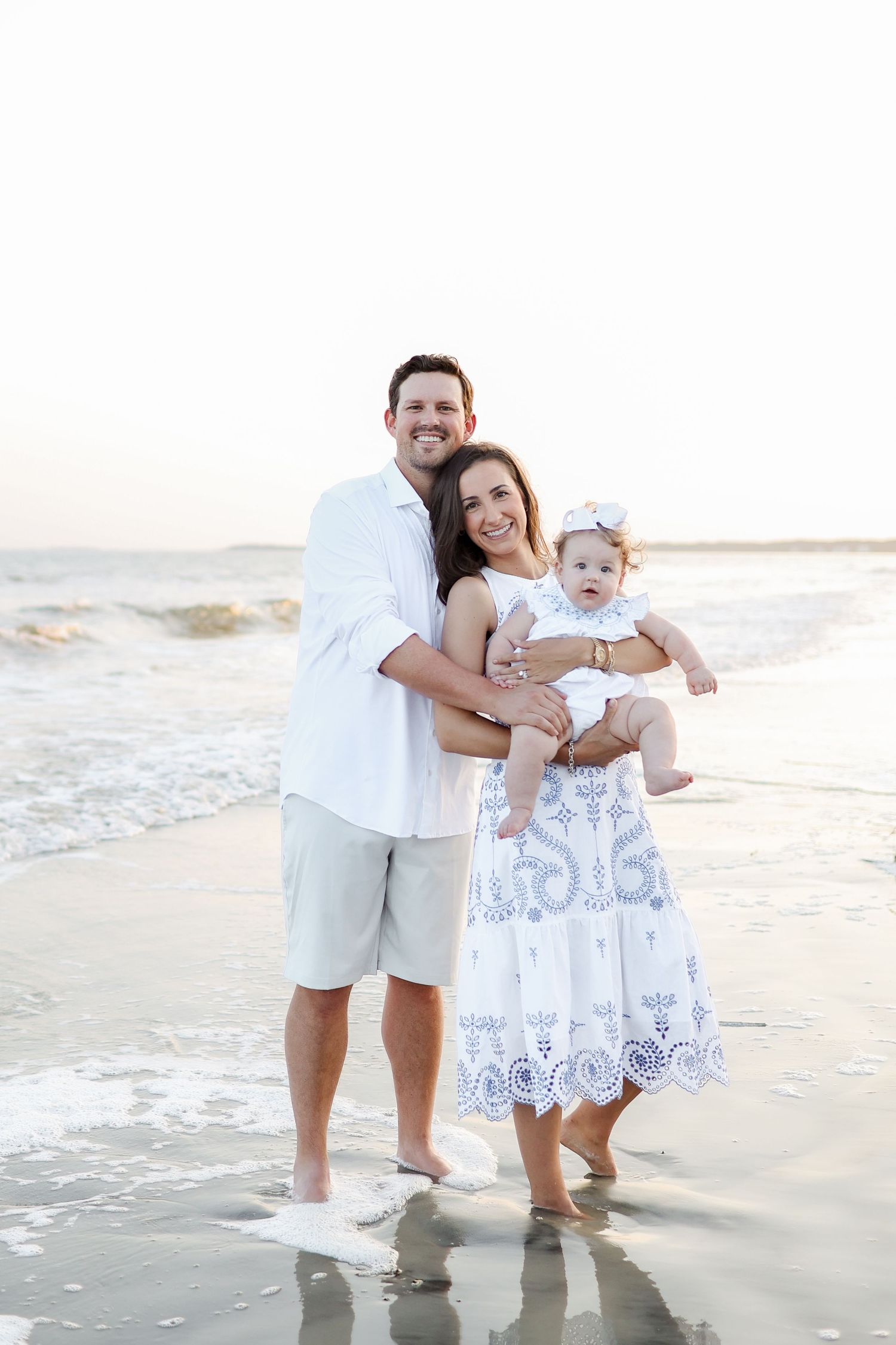 Family standing in shallow ocean water at sunset during a family photo session in Sea Pines on Hilton Head Island