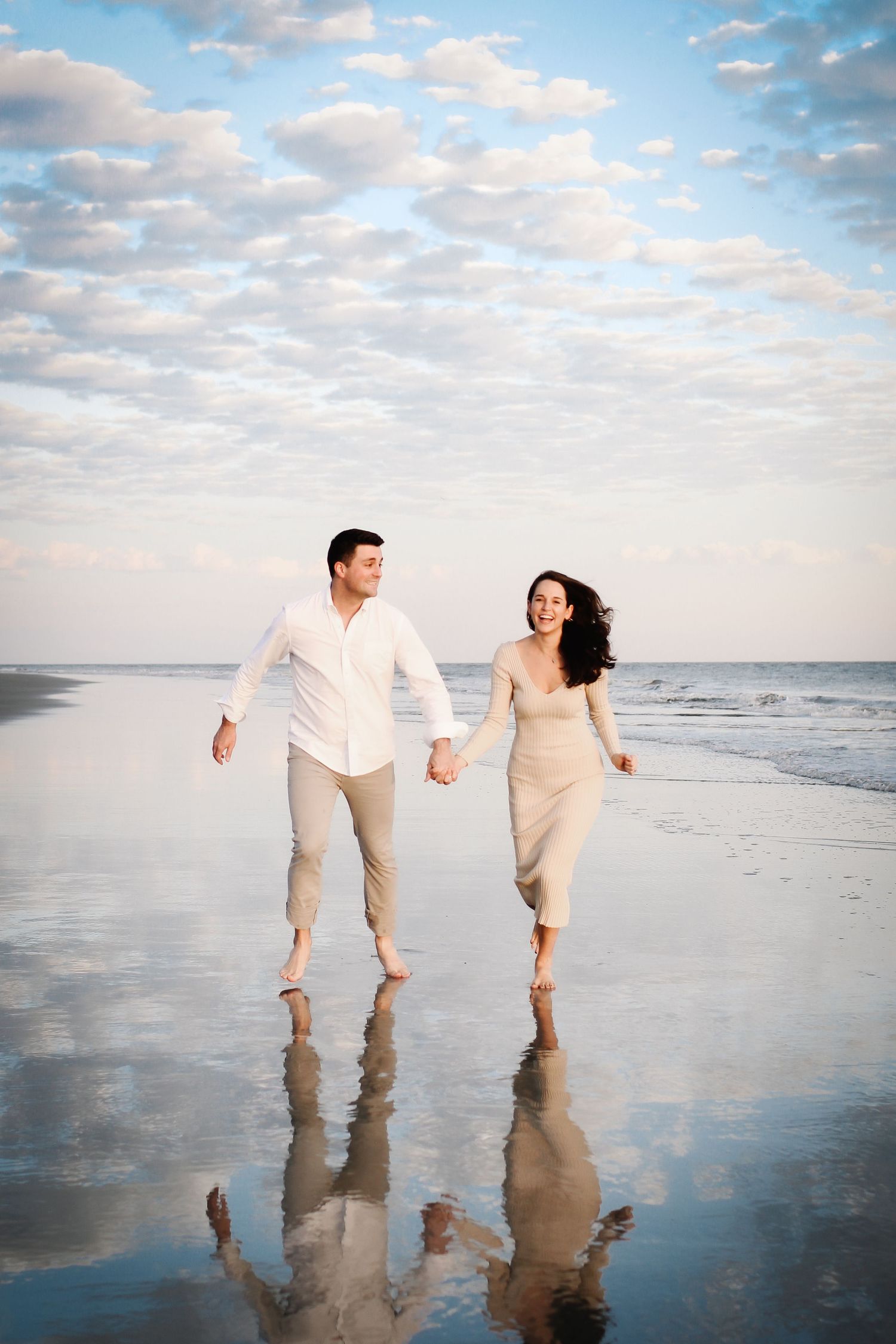 Hilton Head couples and family photography with young couple running along the beach in Sea Pines under a reflective sunset sky