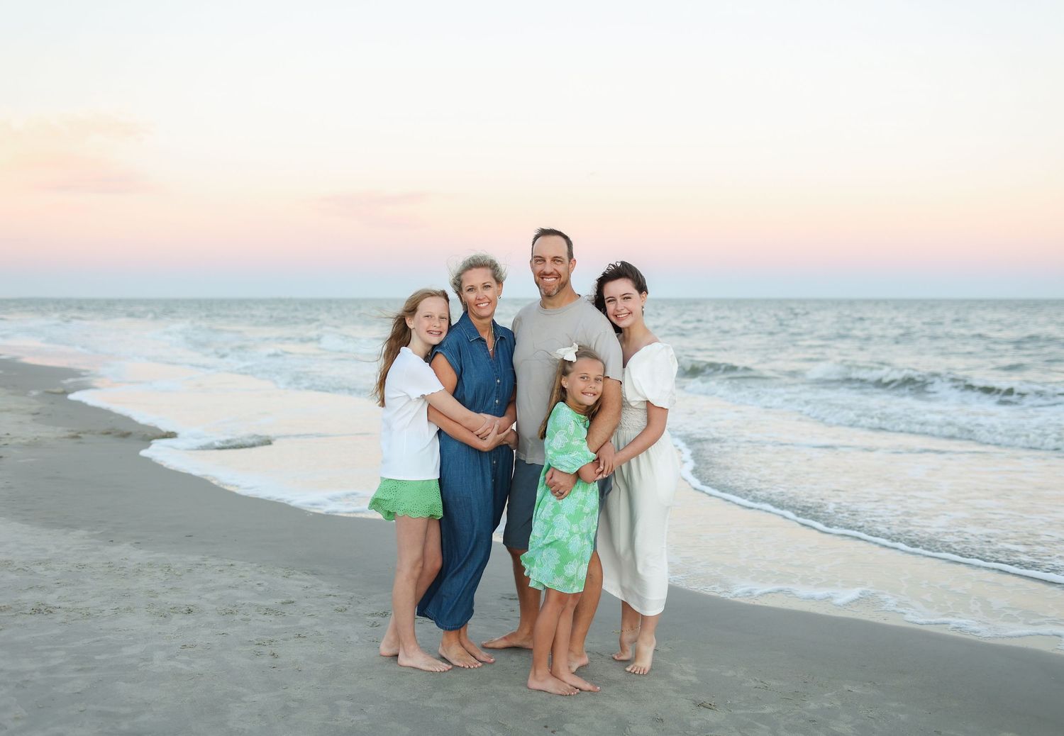 Family photo session on Hilton Head Island with parents and three children standing on the beach at sunset
