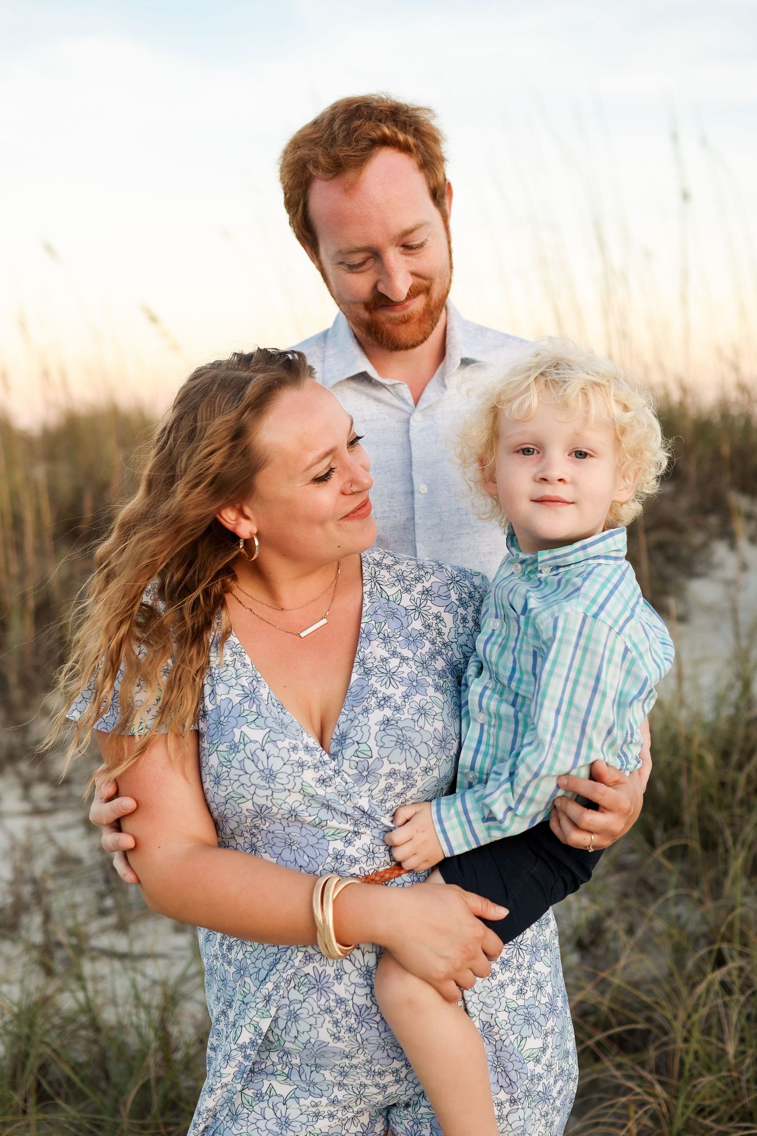 Sunset family photography on Hilton Head with parents holding their toddler in the sand dunes at Folly Field Beach