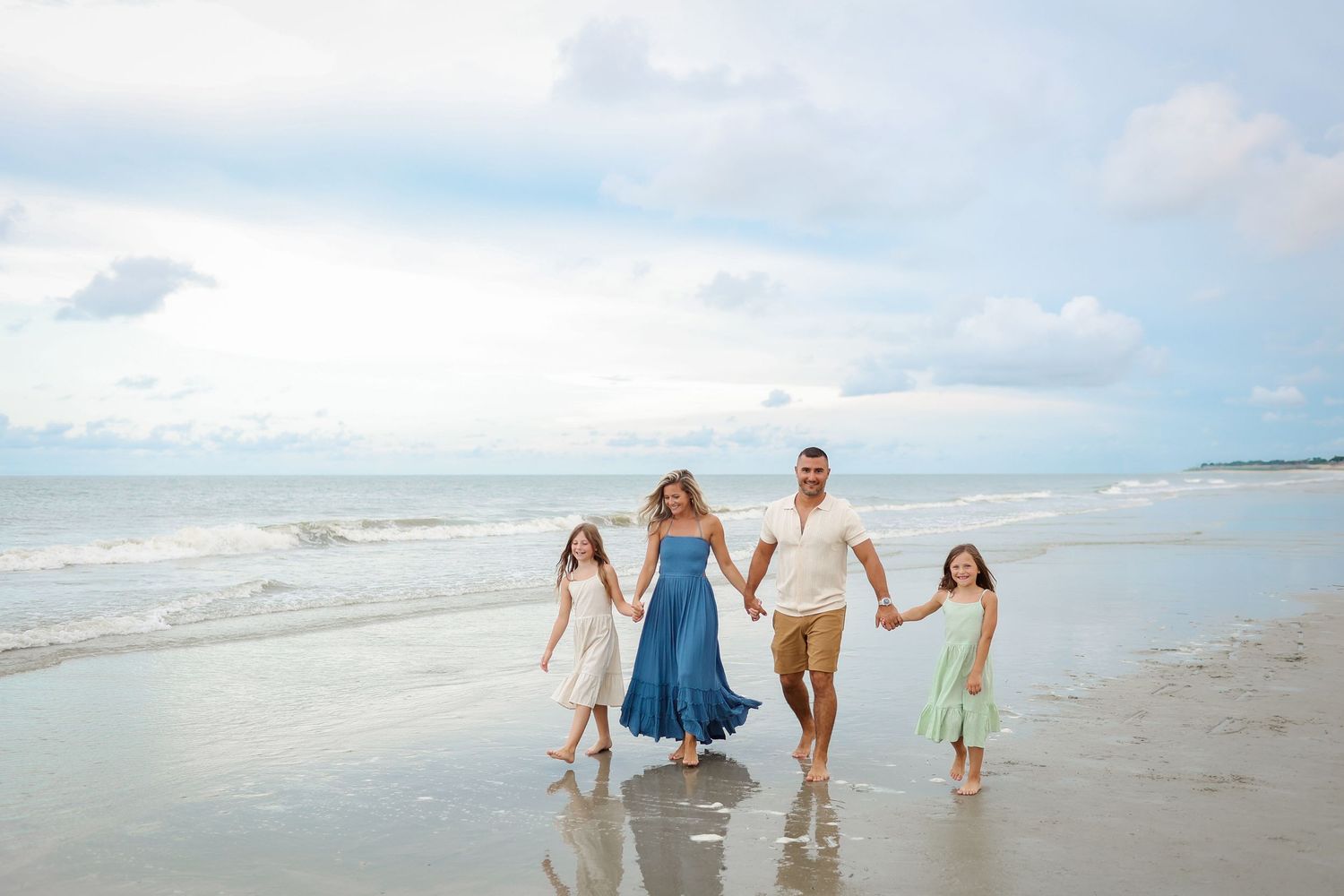 Family photography on Hilton Head as parents and children walk hand in hand along the shoreline at Folly Field Beach