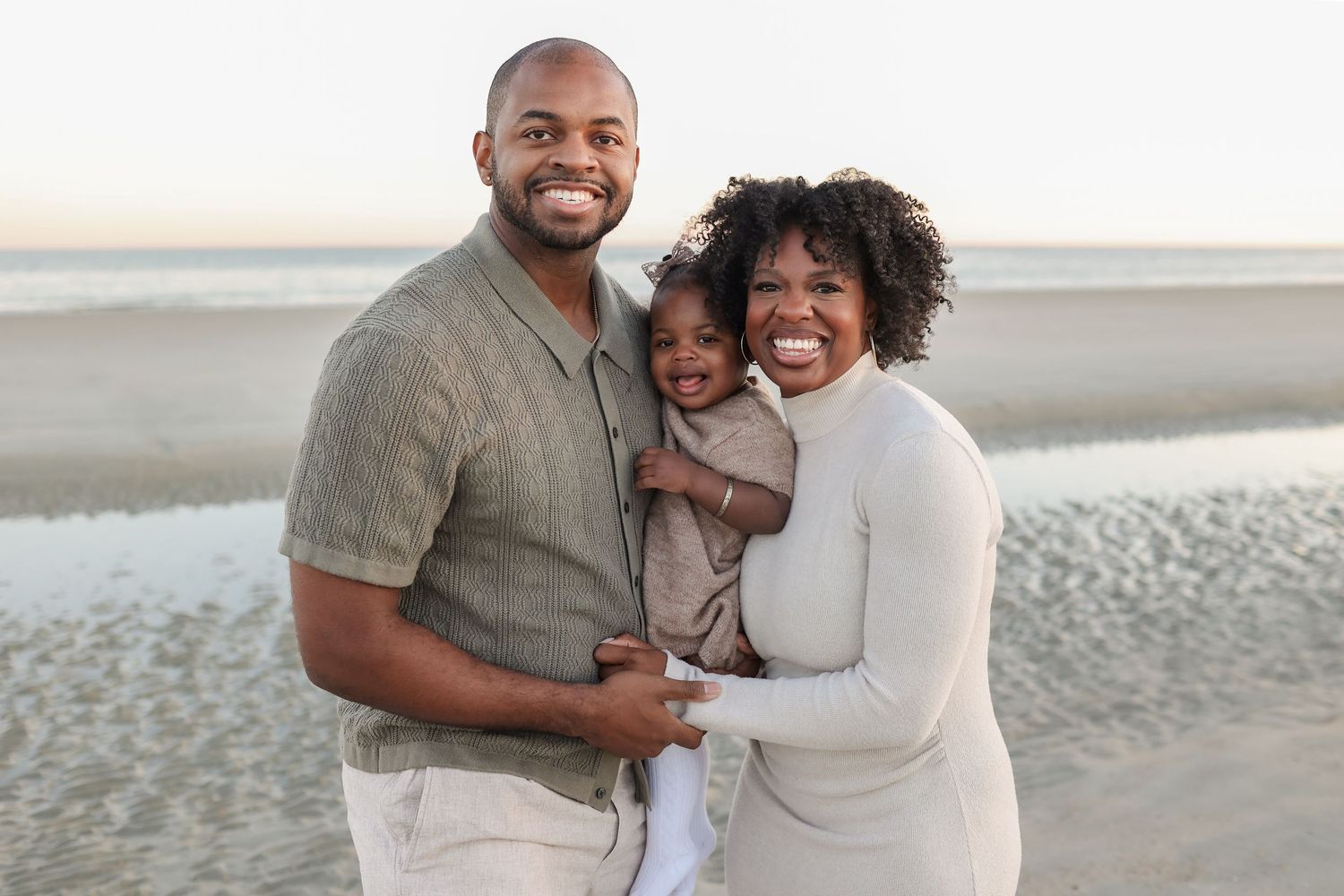 Hilton Head family photographer capturing parents holding their baby on the beach at Burkes Beach