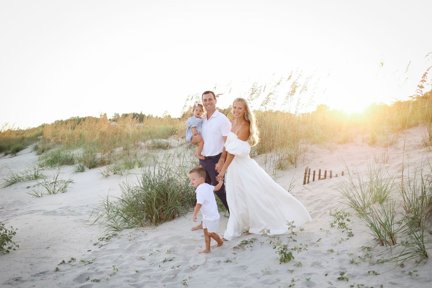 Hilton Head family photography session with young family walking through sand dunes at sunset in Palmetto Dunes