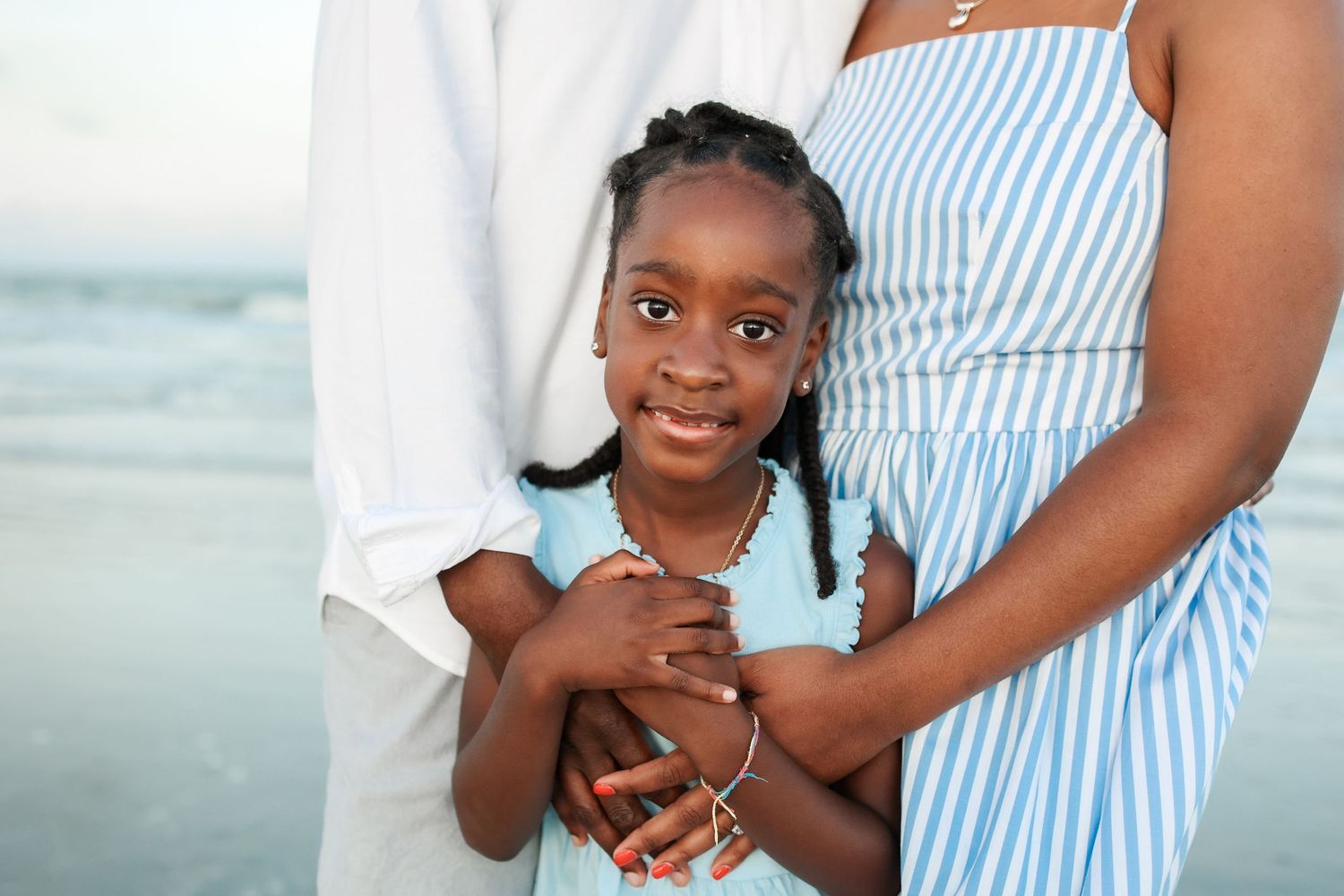 Hilton Head family photos of parents embracing their child during sunset portraits at Palmetto Dunes beach