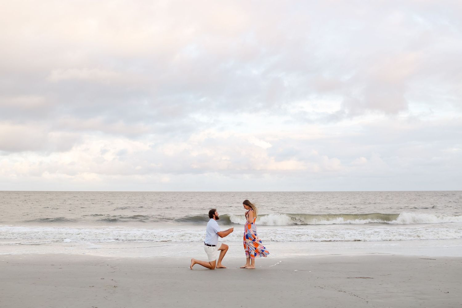 Surprise proposal on Hilton Head Island, man on one knee at sunset with ocean backdrop during engagement photography session
