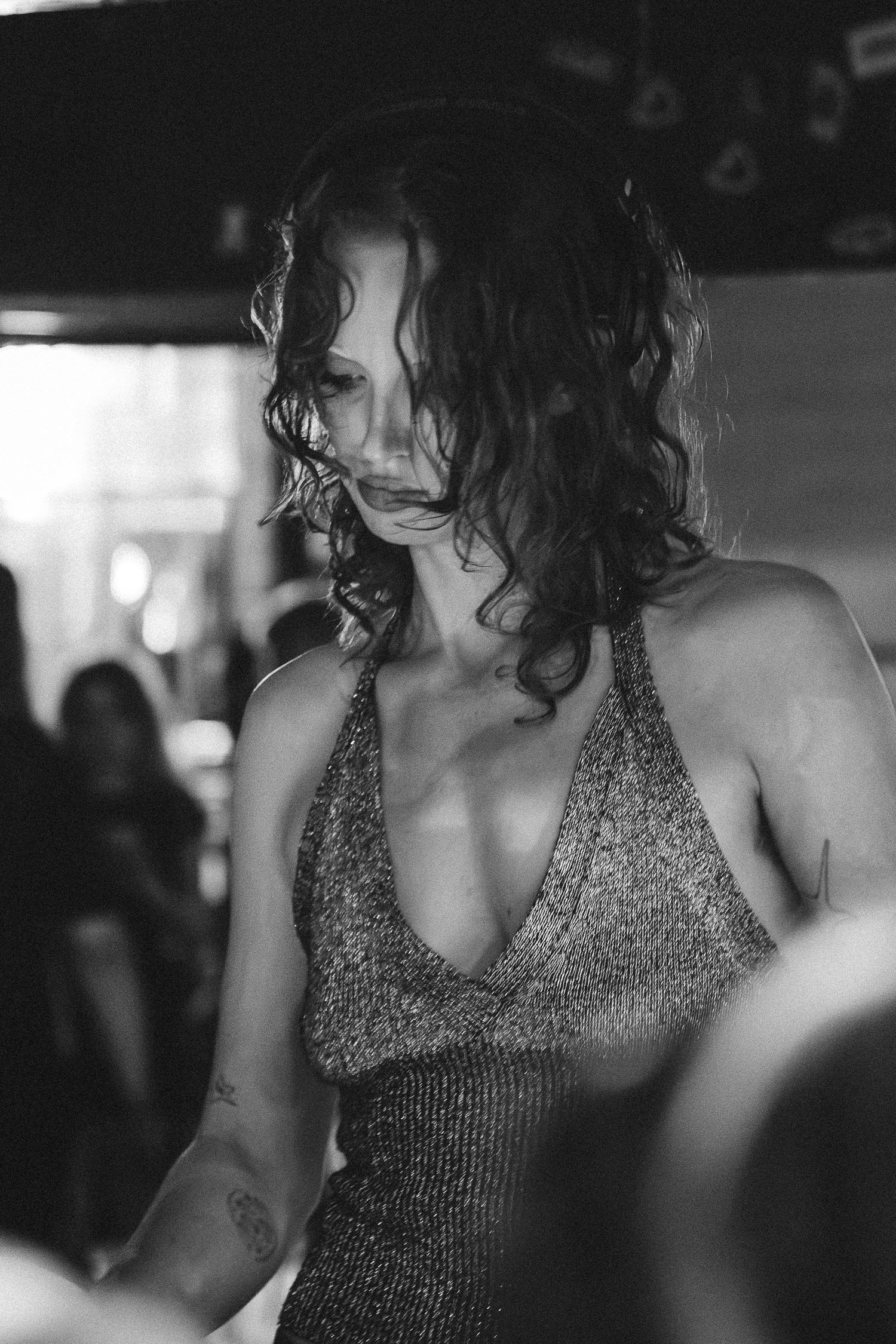 Black and white photo of woman with curly hair in sequin halter dress at The Lass O'Gowrie Hotel.