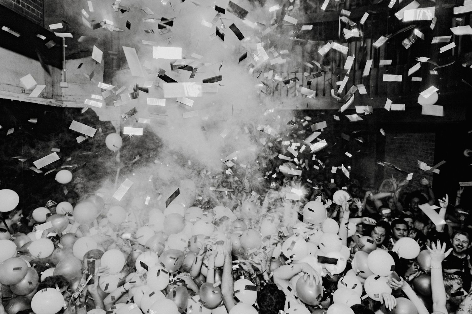 Black and white photo of a crowd celebrating New Years Evewith confetti and balloons at King Street Hotel, Newcastle.