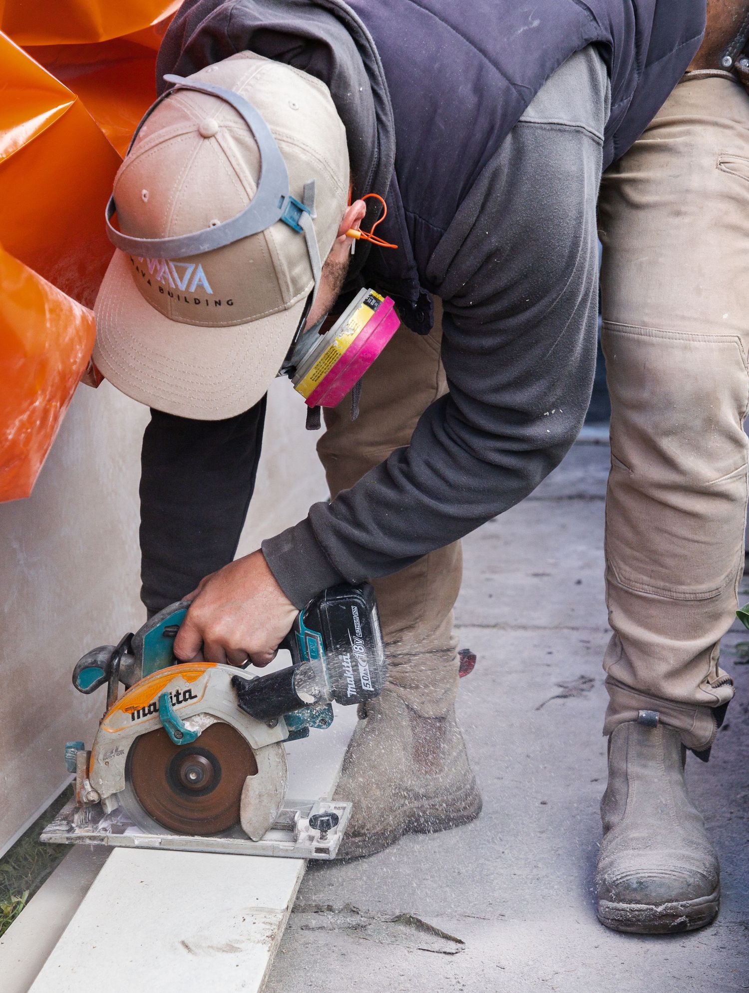 Worker using a Makita circular saw to cut material on a construction site.