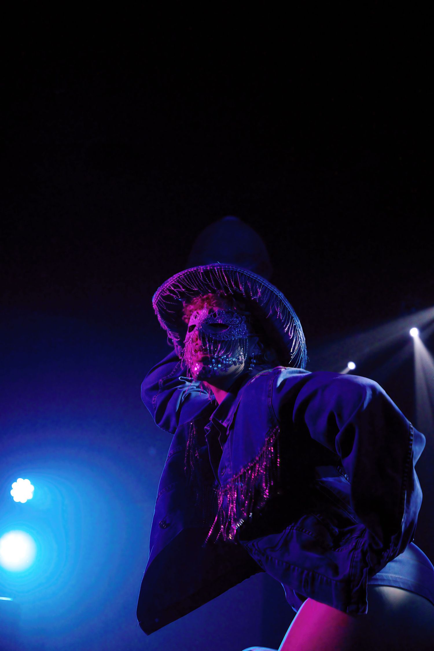 Masked performer on stage bathed in blue and pink lights during dramatic nightclub show at The Station Hotel for Poof Doof.