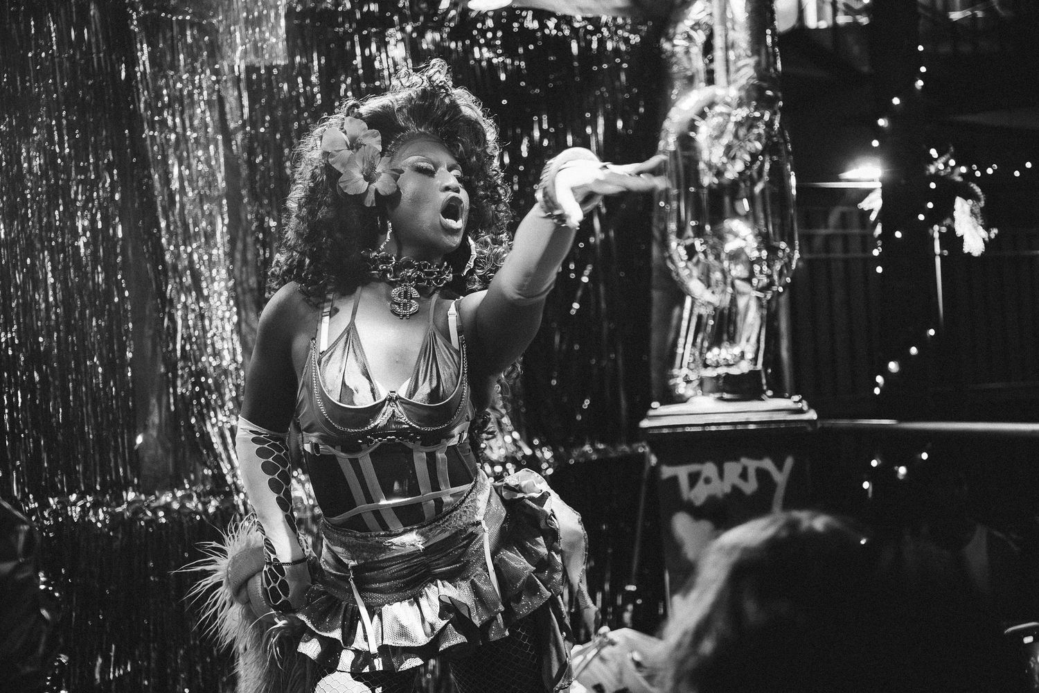 Black and white photo of a performer in a corset singing on stage at a glittery nightclub event at The Lass O'Gowrie Hotel.