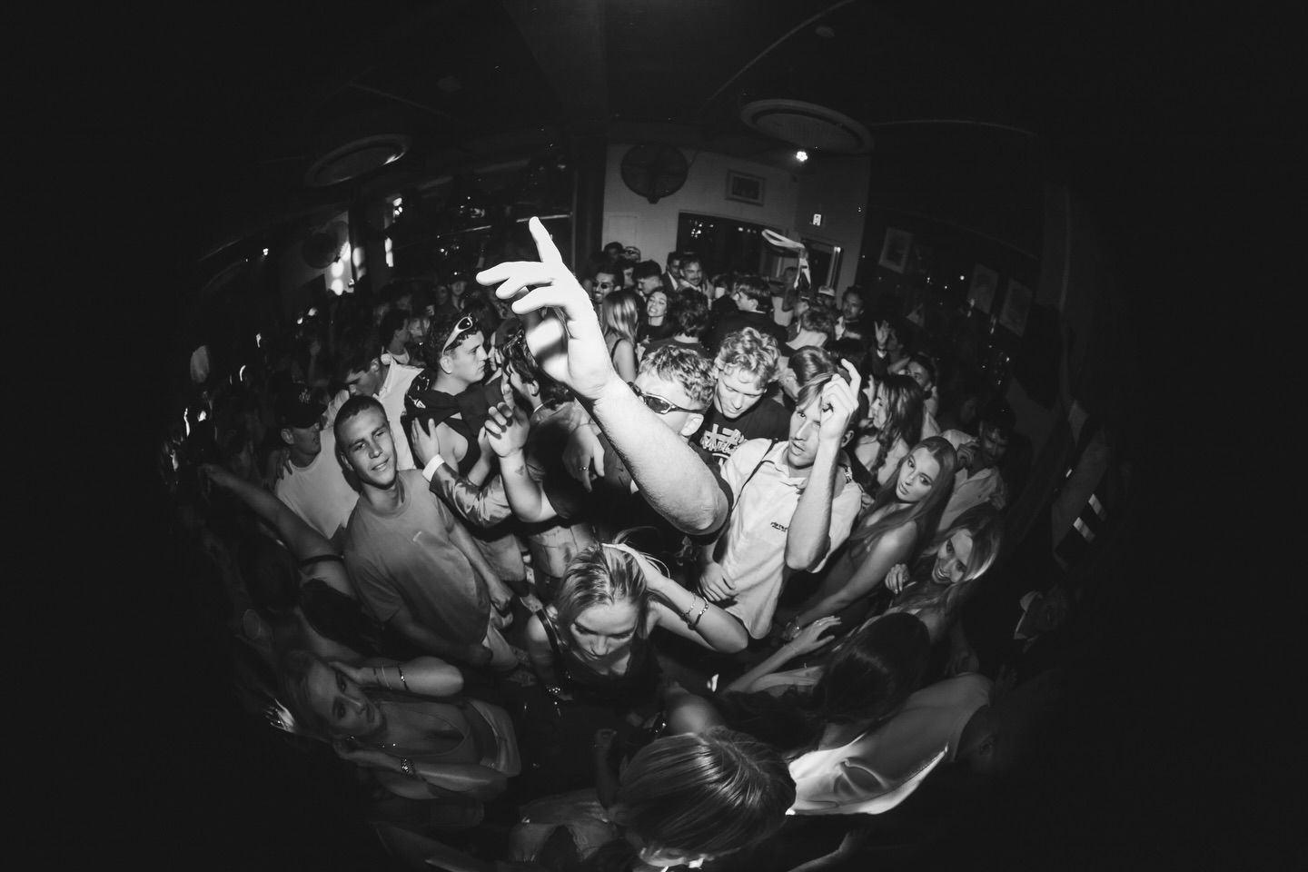 Black and white fisheye lens photo of an energetic crowd at a packed live music venue, The Beach Hotel Merewether.