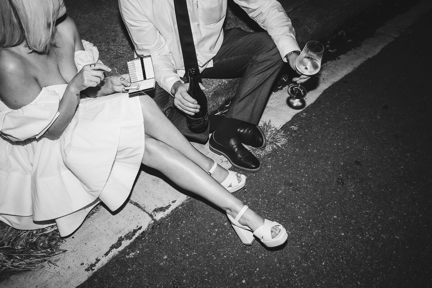 Black and white wedding photo of couple sitting on curb at night, high flash photo by Newcastle photographer Alyse Filipuzzi