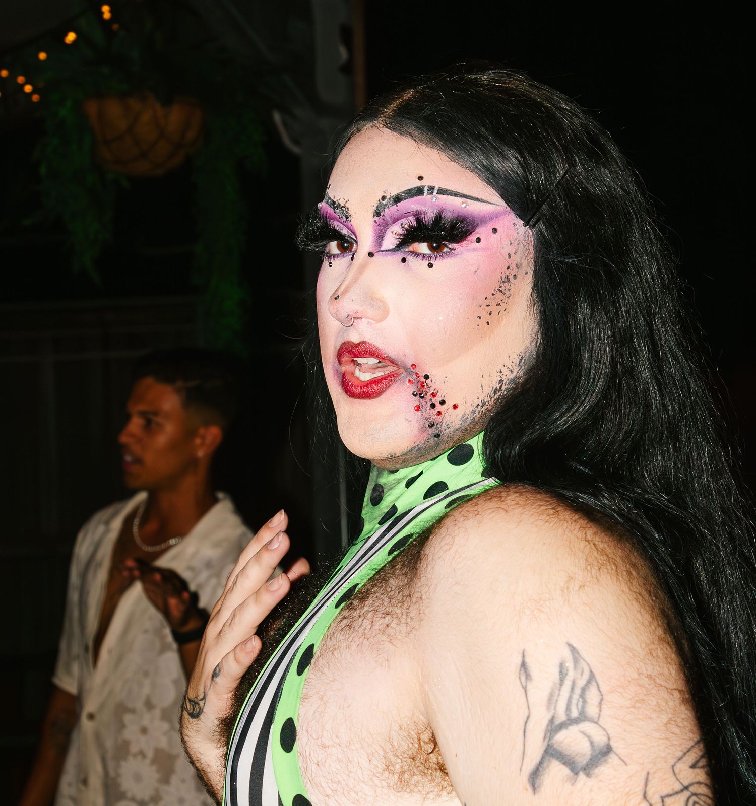 Drag performer with elaborate spider web eye makeup and green polka dot outfit at nightclub event at The Lass O'Gowrie Hotel.