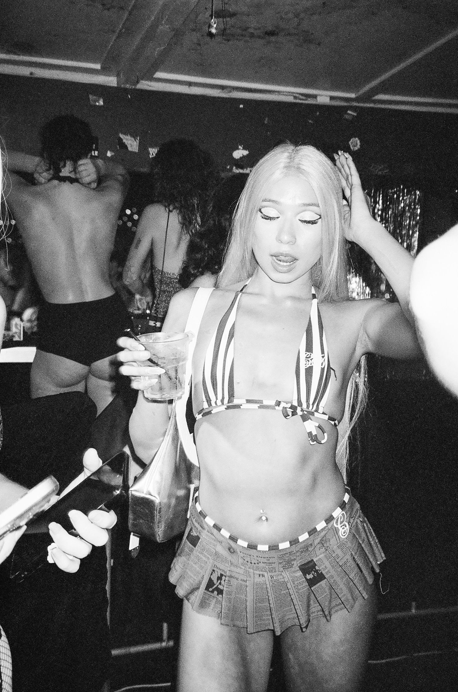 Black and white photo of a blonde performer in a bikini top and skirt dancing at a nightclub The Lass O'Gowrie Hotel.