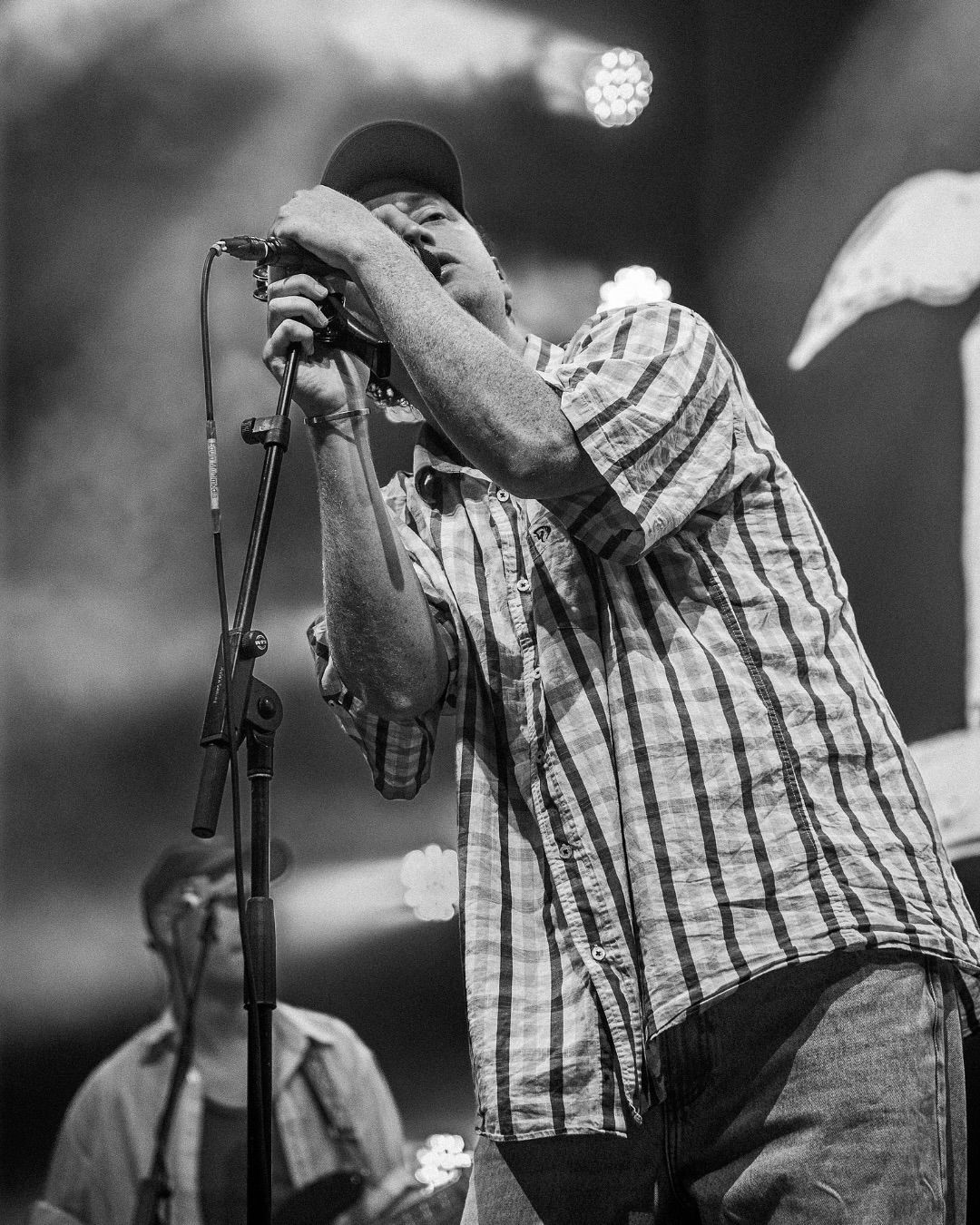 Black and white photo of male vocalist of DMAs singing passionately into microphone on stage.