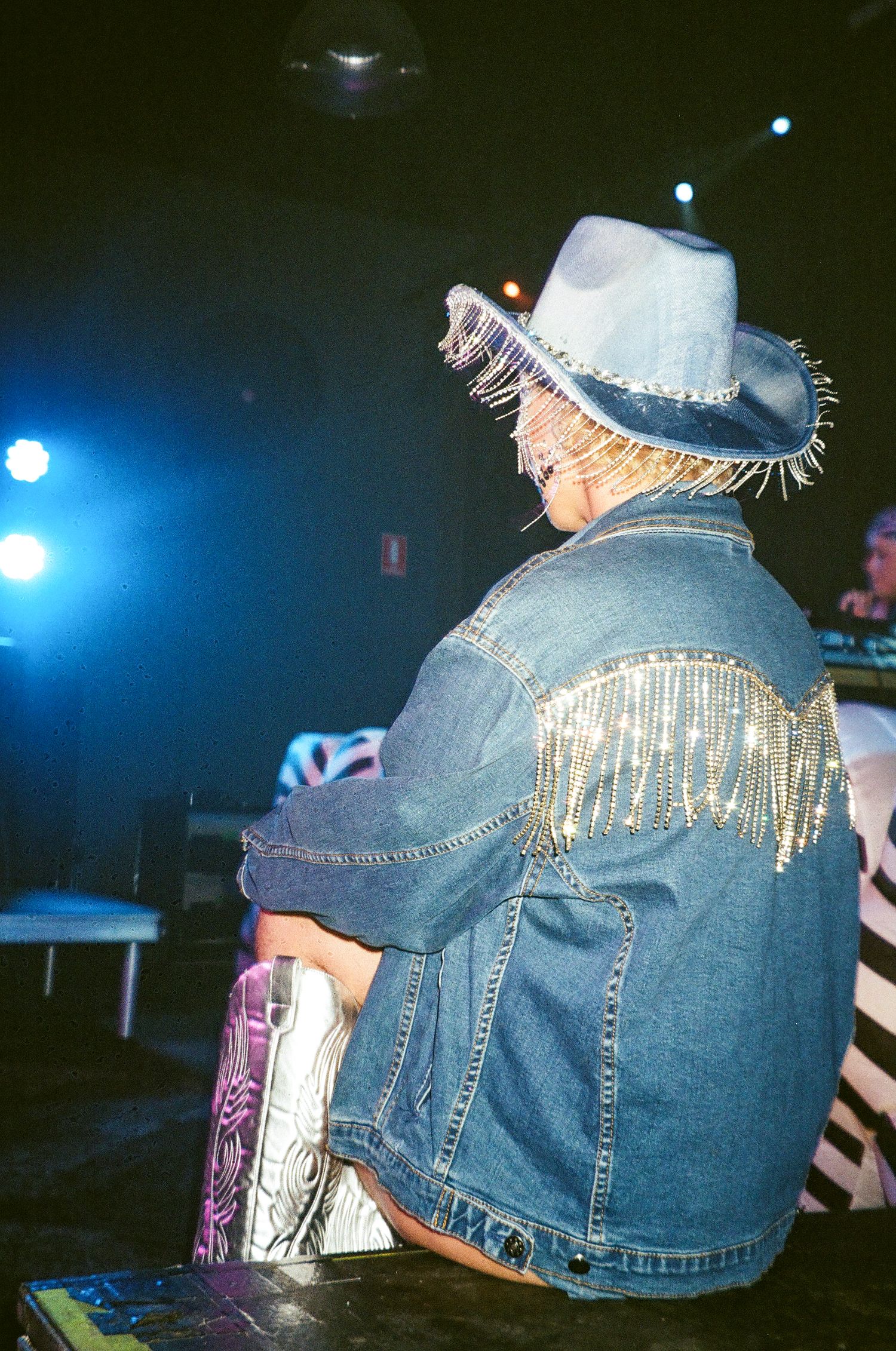 Person wearing bedazzled denim jacket and cowboy hat with fringe detail at The Station Hotel for Poof Doof.