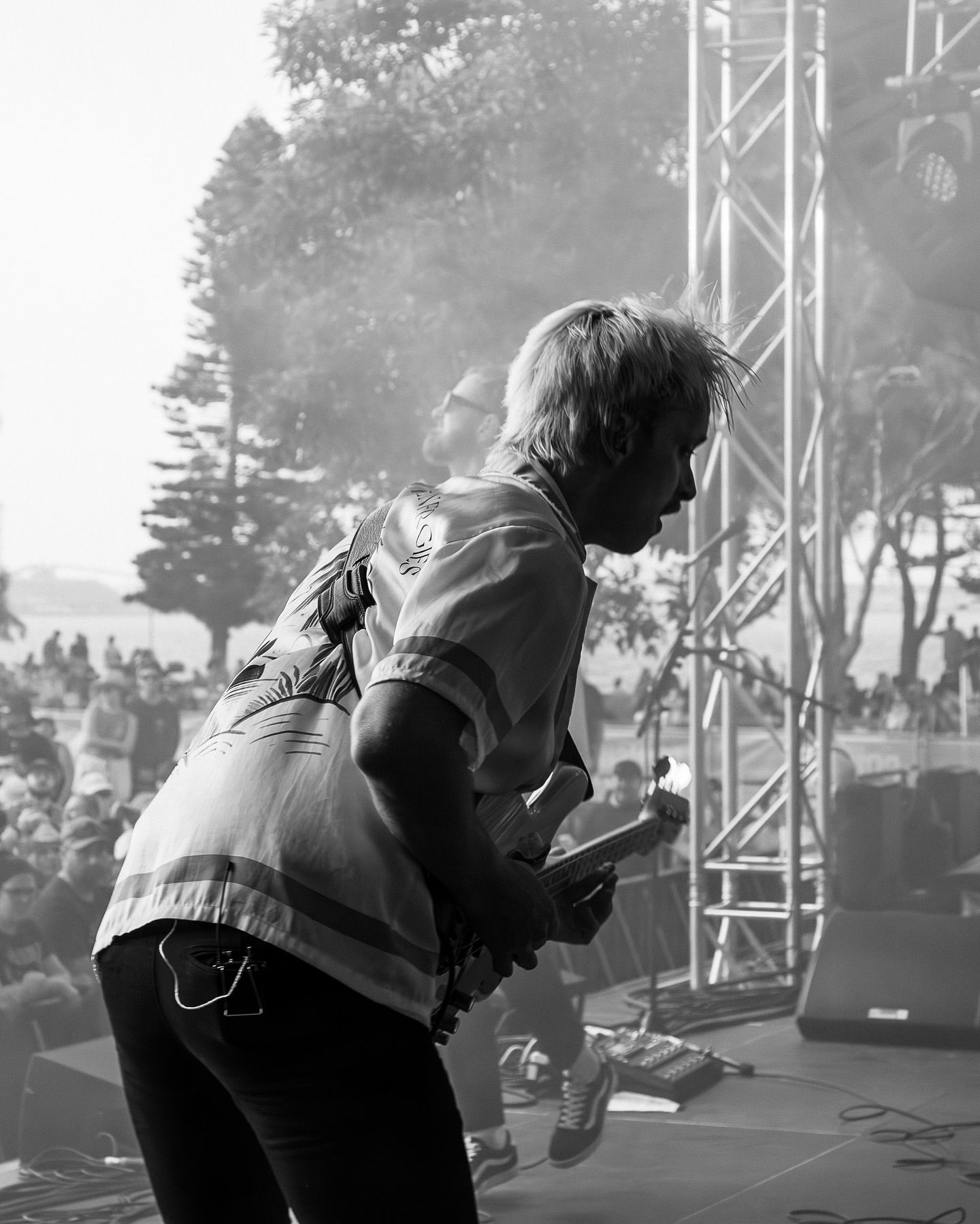 Black and white photo of Guitarist from Birds of Toky leaning into performance on outdoor festival stage.