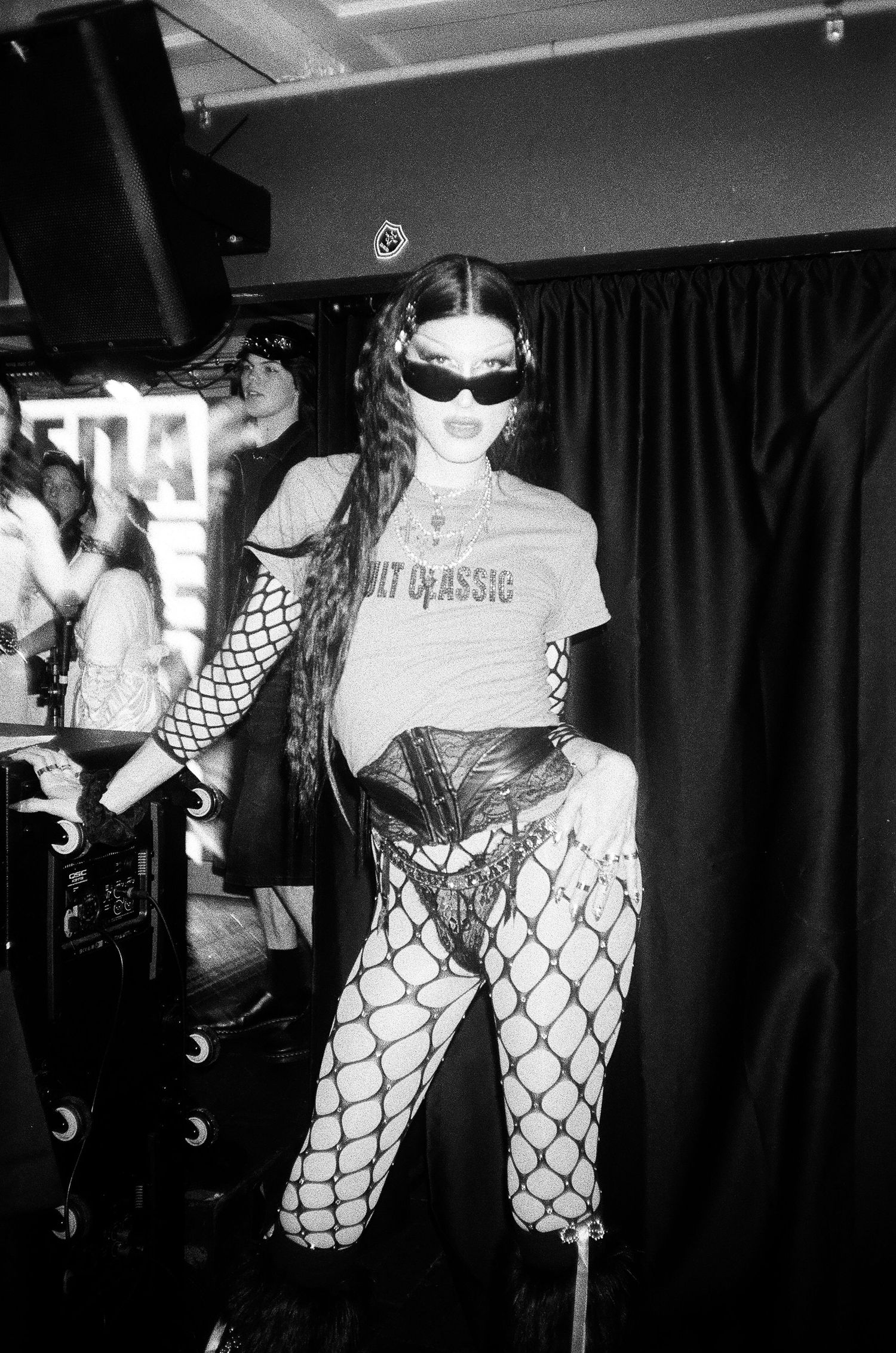 Black and white photo of a performer in fishnet tights and corset on stage at The Lass O'Gowrie Hotel.