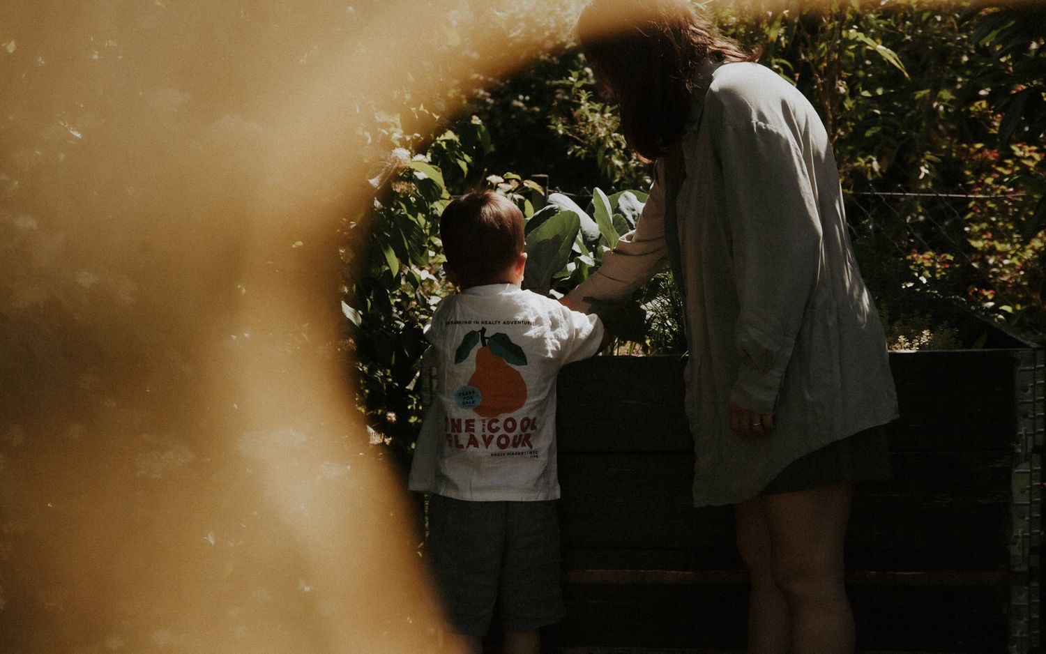 Kind und Mutter beobachten Garten durch ein rundes Spiegelfenster im Gegenlicht