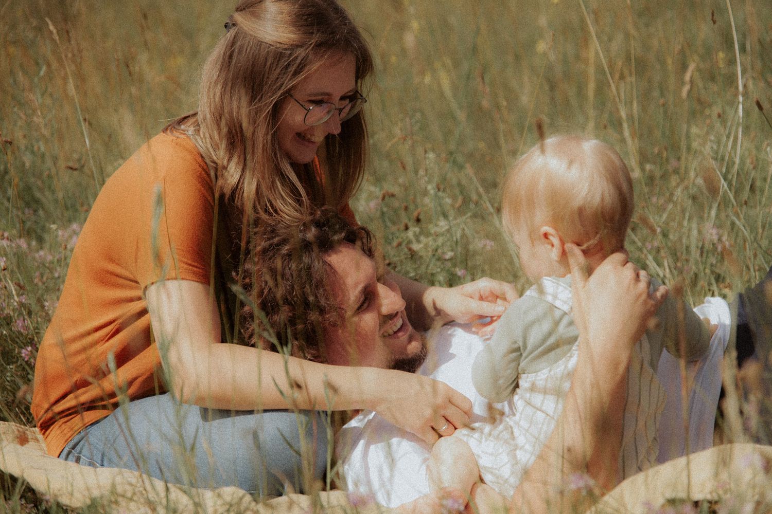 Familie lacht zusammen im hohen Gras – authentisches Familienshooting Ingolstadt