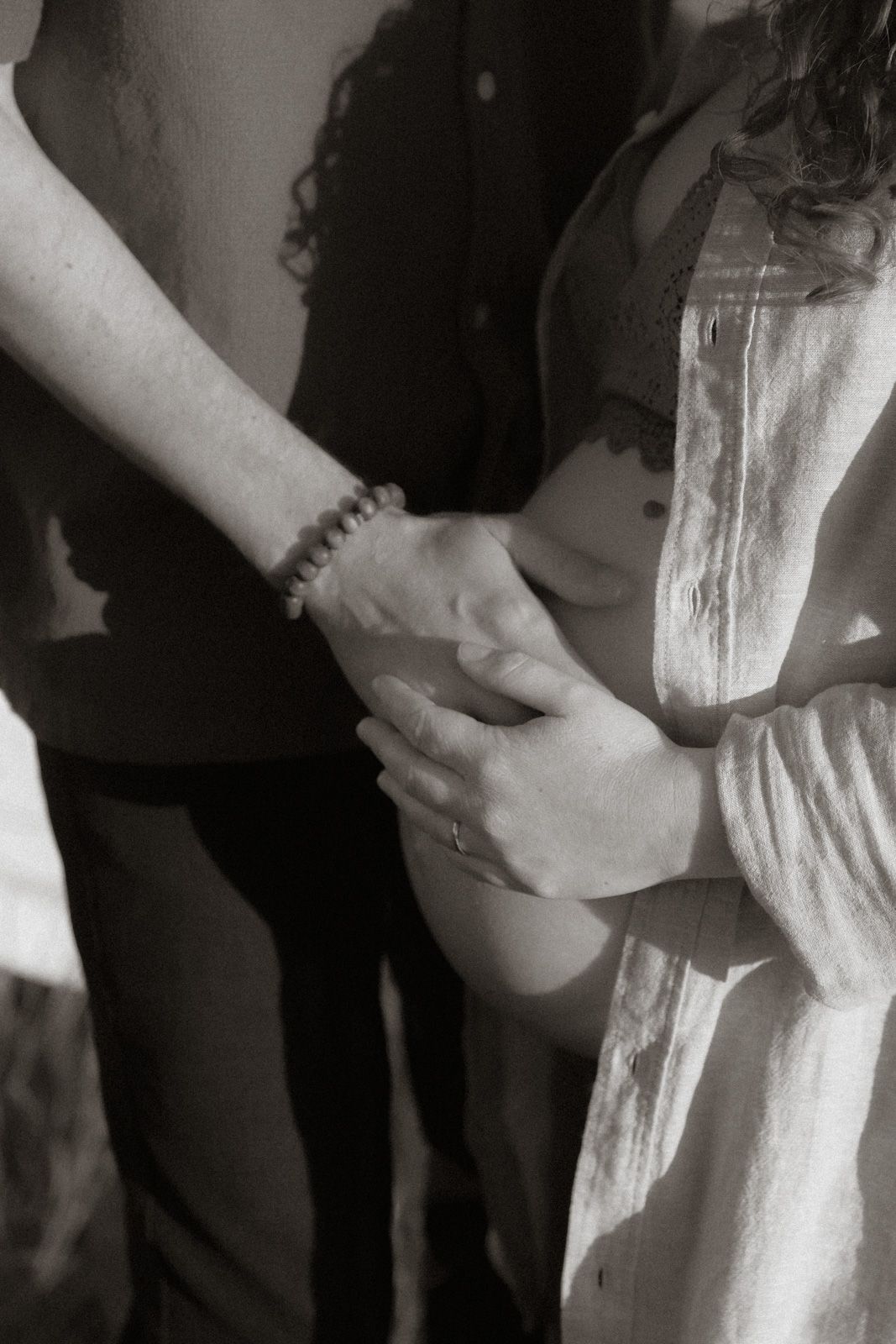 Hände umfassen zärtlich den Babybauch – Schwarz-Weiß Schwangerschaftsfotografie Ingolstadt